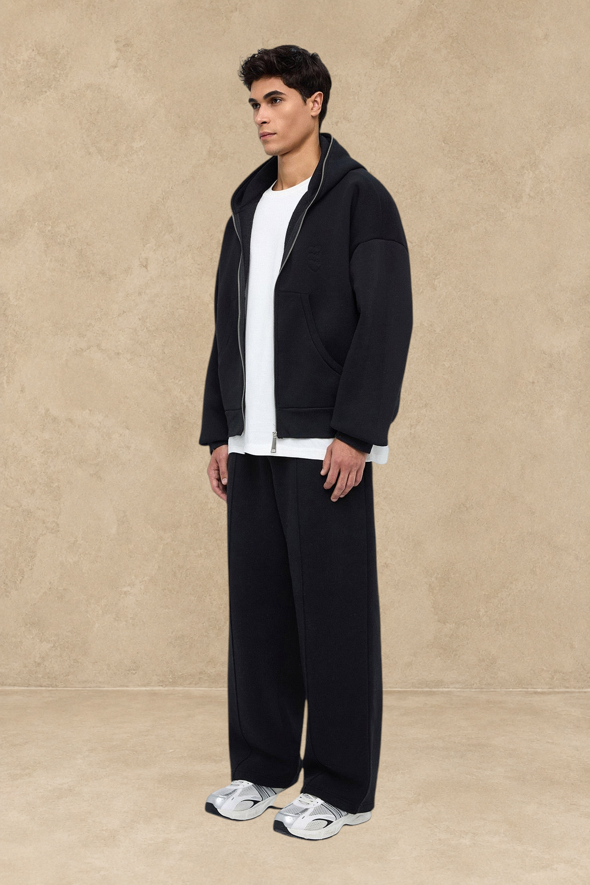Homme portant un pantalon jogging large noir Stayin avec un sweat à capuche zippé assorti et des baskets