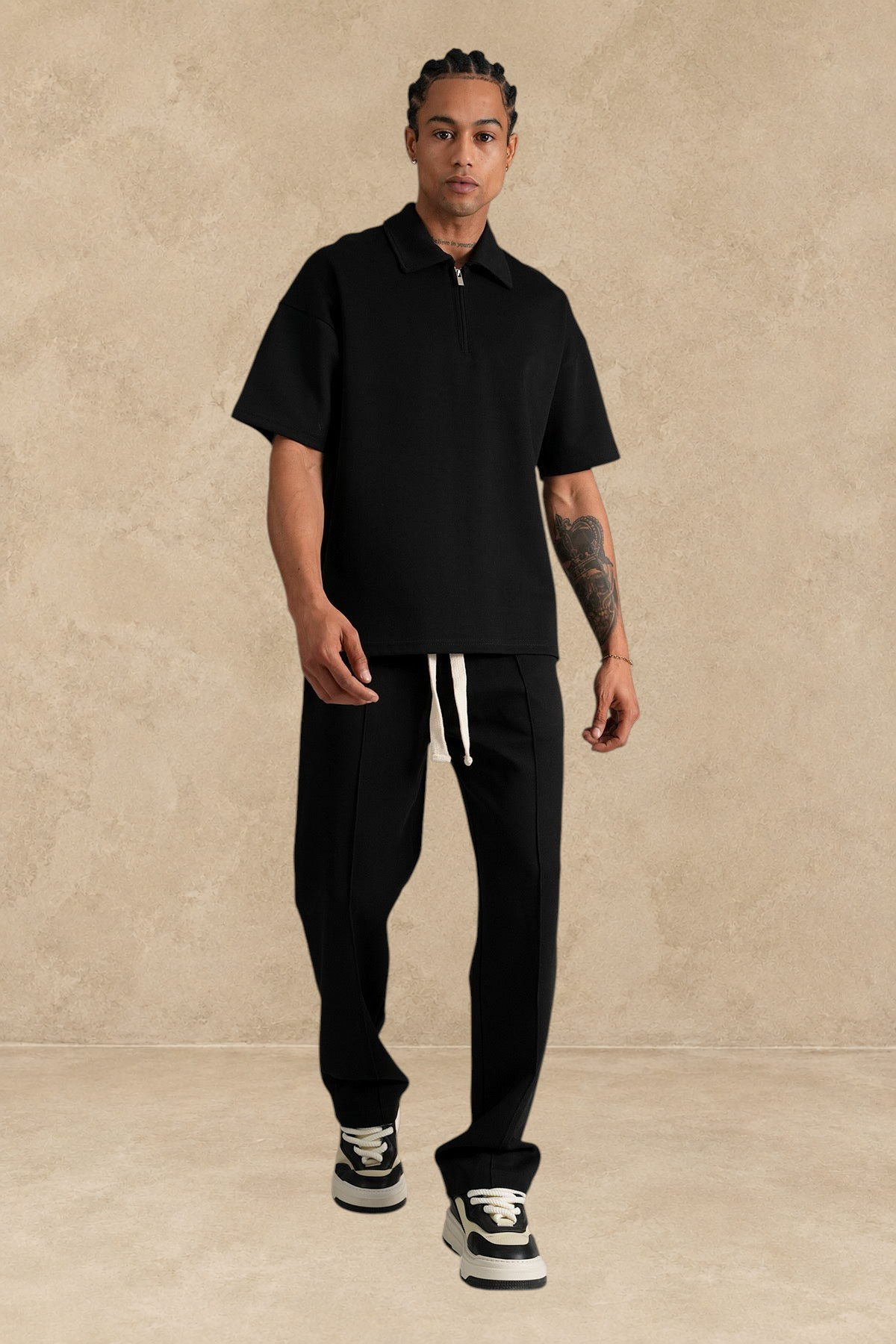 Ensemble Stayin noir coupe large avec polo zippé et pantalon en polyester porté par un mannequin