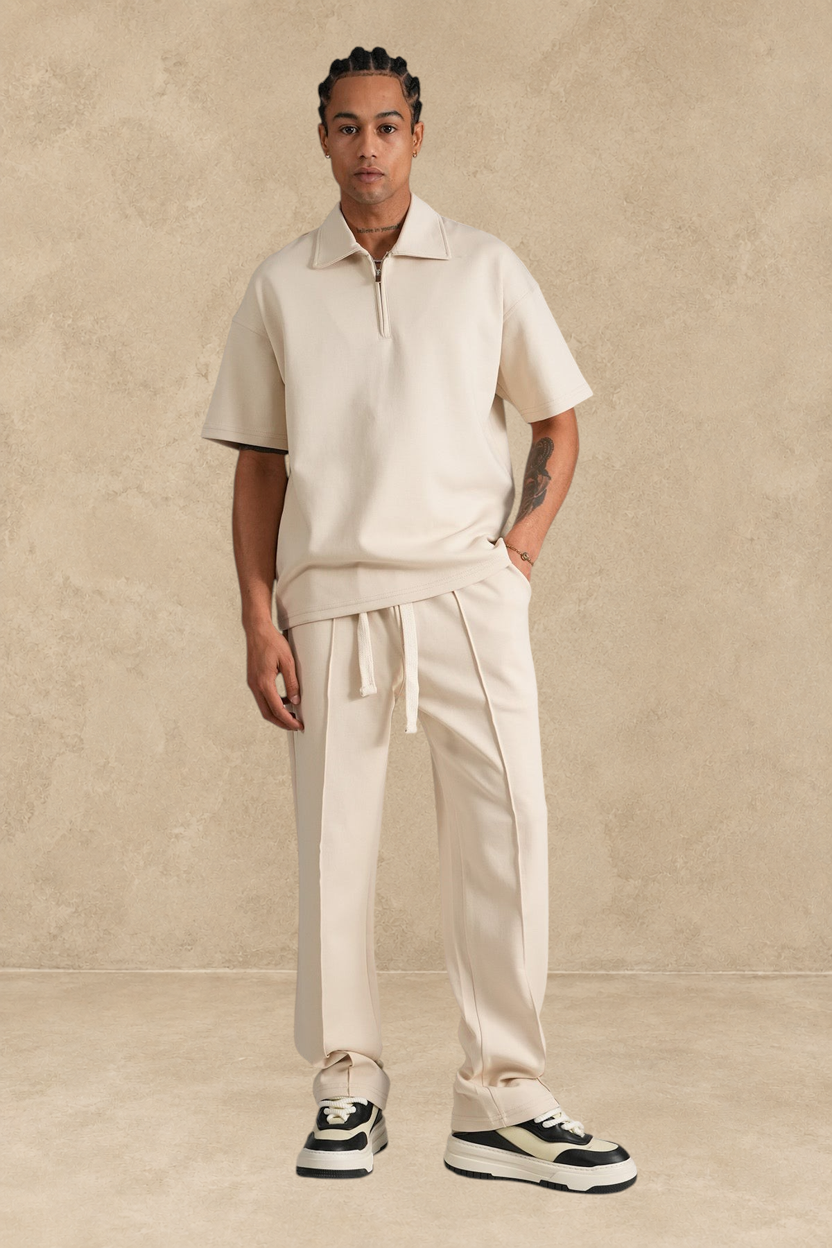 Ensemble Stayin beige composé d'un polo à zip et d'un pantalon coupe large en polyester porté par un mannequin