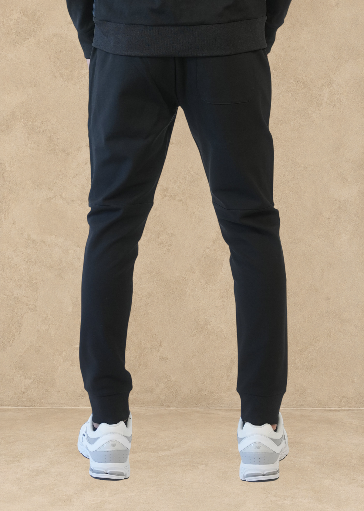 Vue arrière du pantalon de jogging noir Helvetica Megeve porté avec des baskets blanches par Stayin