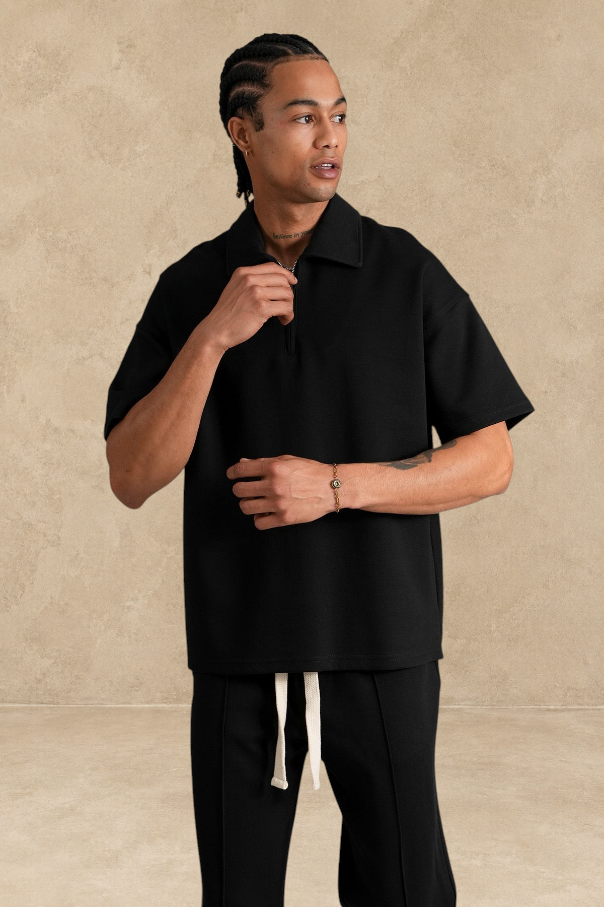 Mannequin portant un ensemble Stayin noir composé d'un polo à zip et d'un pantalon coupe large en polyester