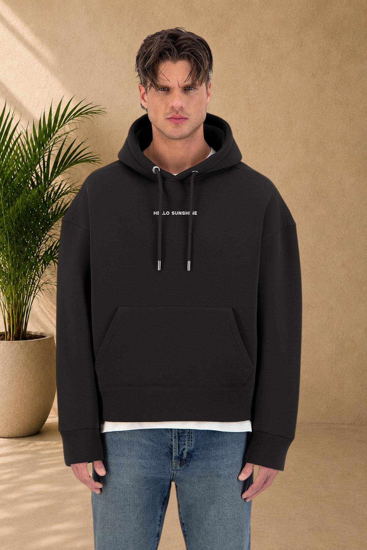 Stayin black quilted hoodie with Hello Sunshine print, worn by a male model in a studio setting.