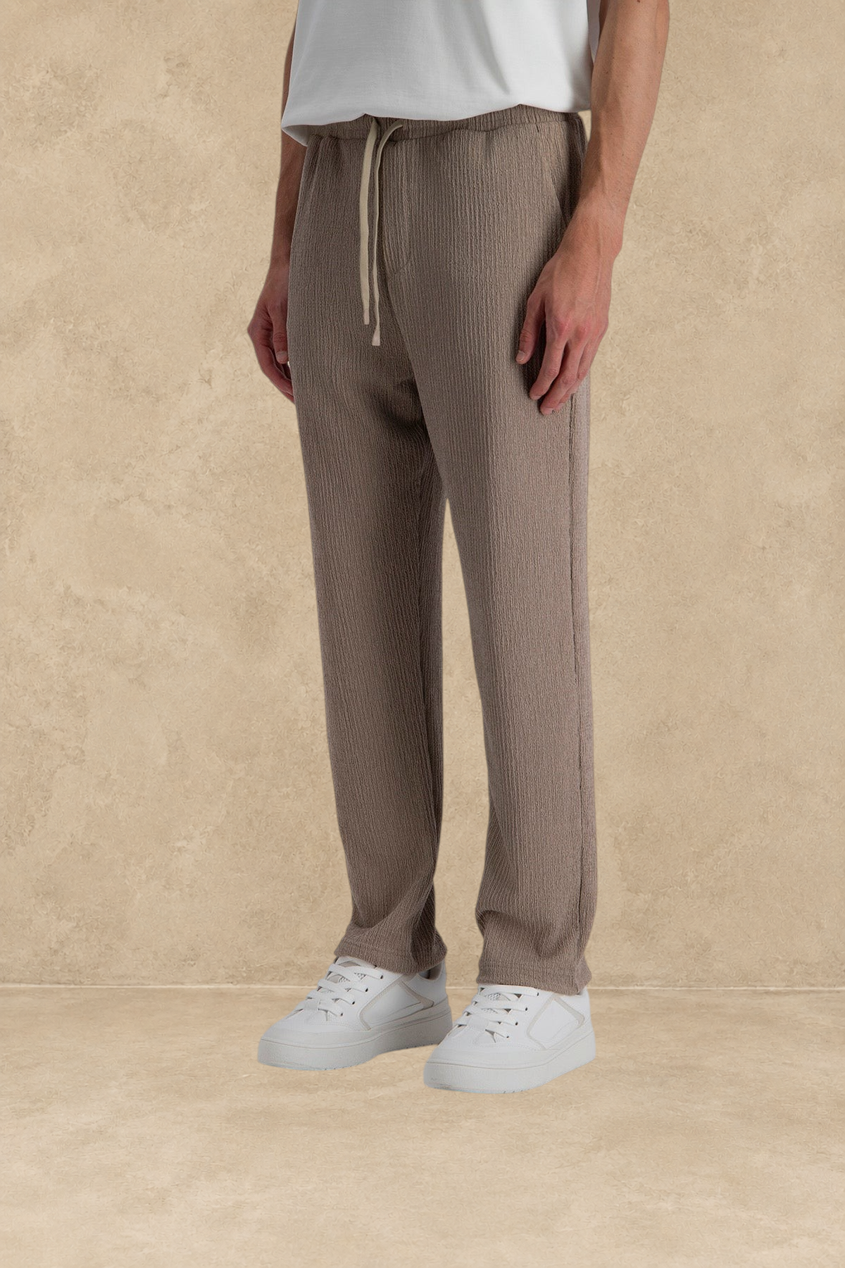 Pantalon plissé marron Stayin à coupe regular avec cordon de serrage, porté par un mannequin avec des baskets blanches