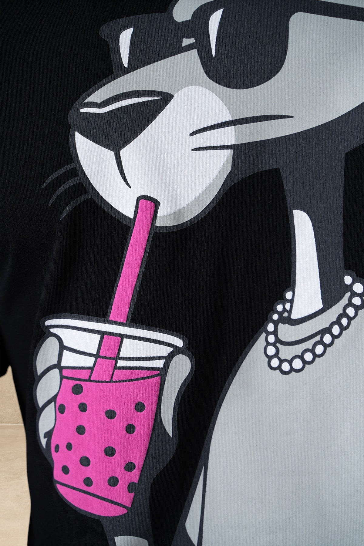 Gros plan sur le t-shirt noir en coton Stayin avec imprimé Panthère Rose buvant un bubble tea