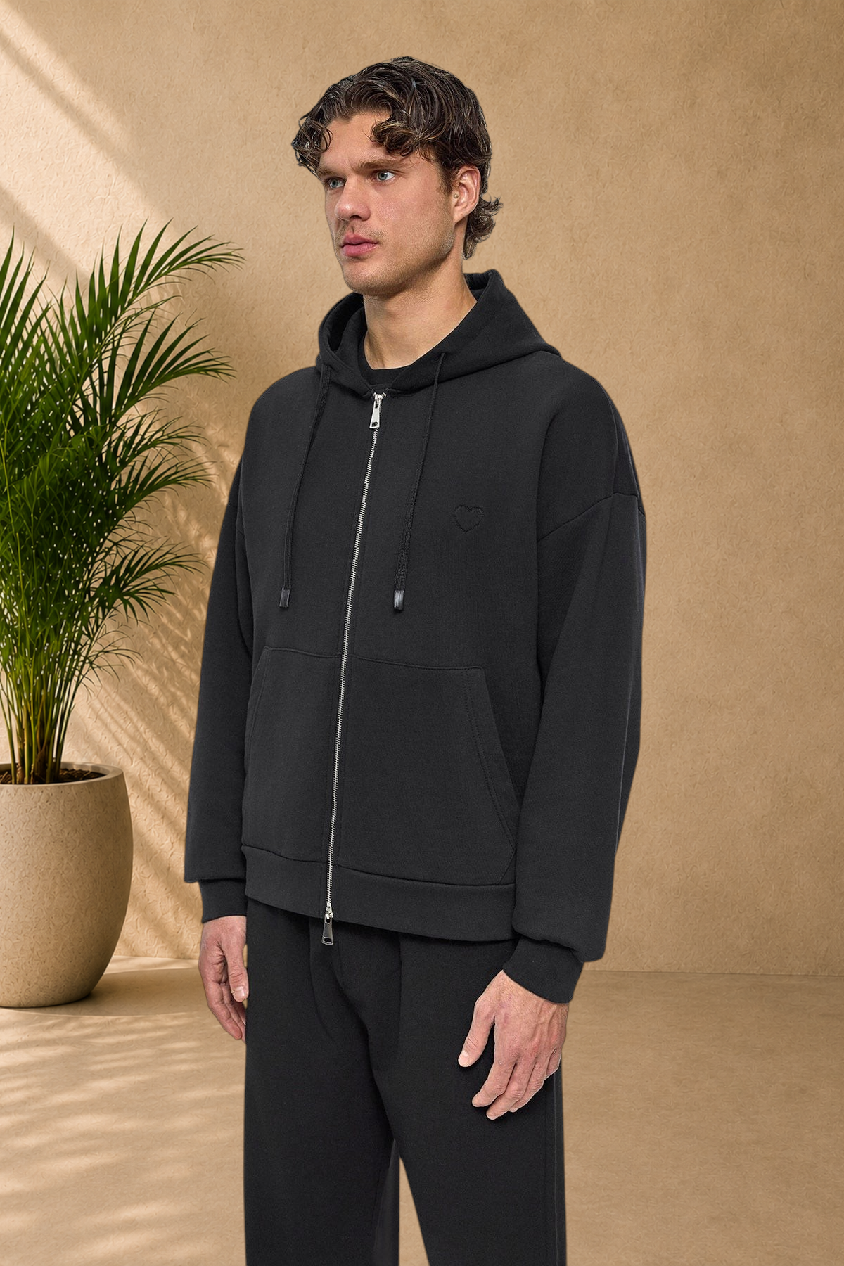 Stayin black quilted zip-up hoodie with a small heart detail on the chest worn by a male model
