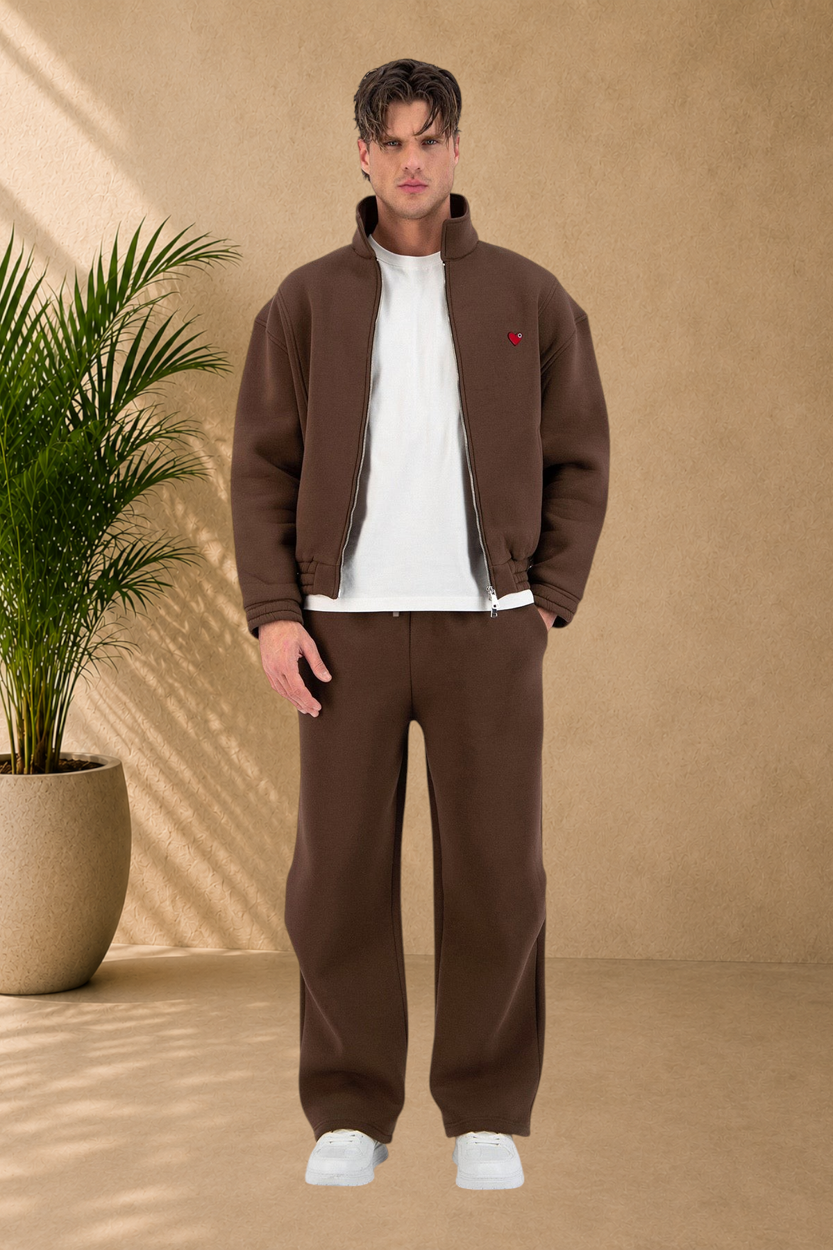 Stayin brown oversized padded jacket with a small heart detail worn by a male model in a studio setting