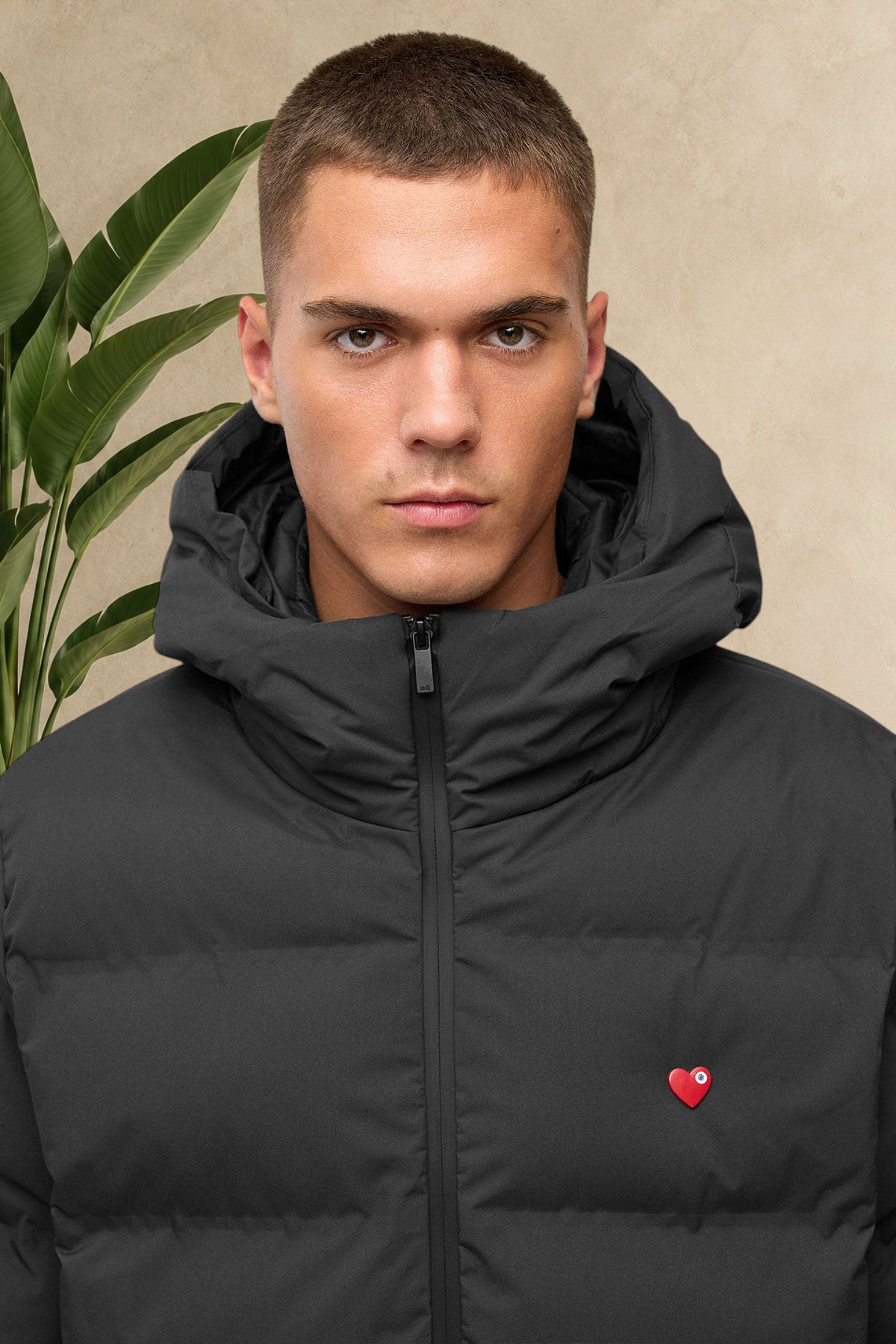 Doudoune longue noire Stayin avec capuche, col montant et logo cœur rouge sur la poitrine portée par un homme