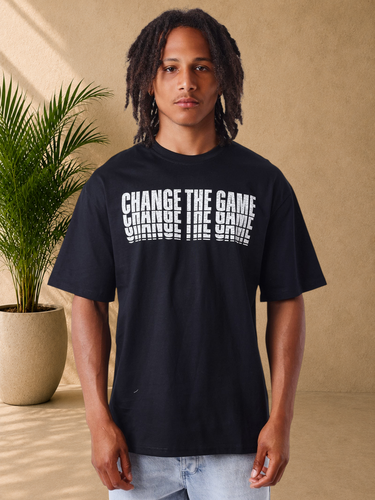 Stayin model wearing a black PXP cotton t-shirt with a white distressed Change The Game graphic on the chest