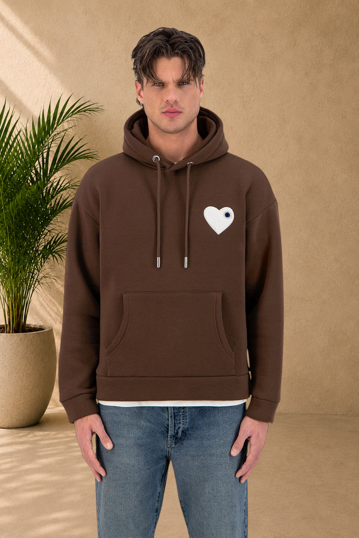 Stayin brown quilted hoodie featuring a white heart patch on the chest worn by a male model