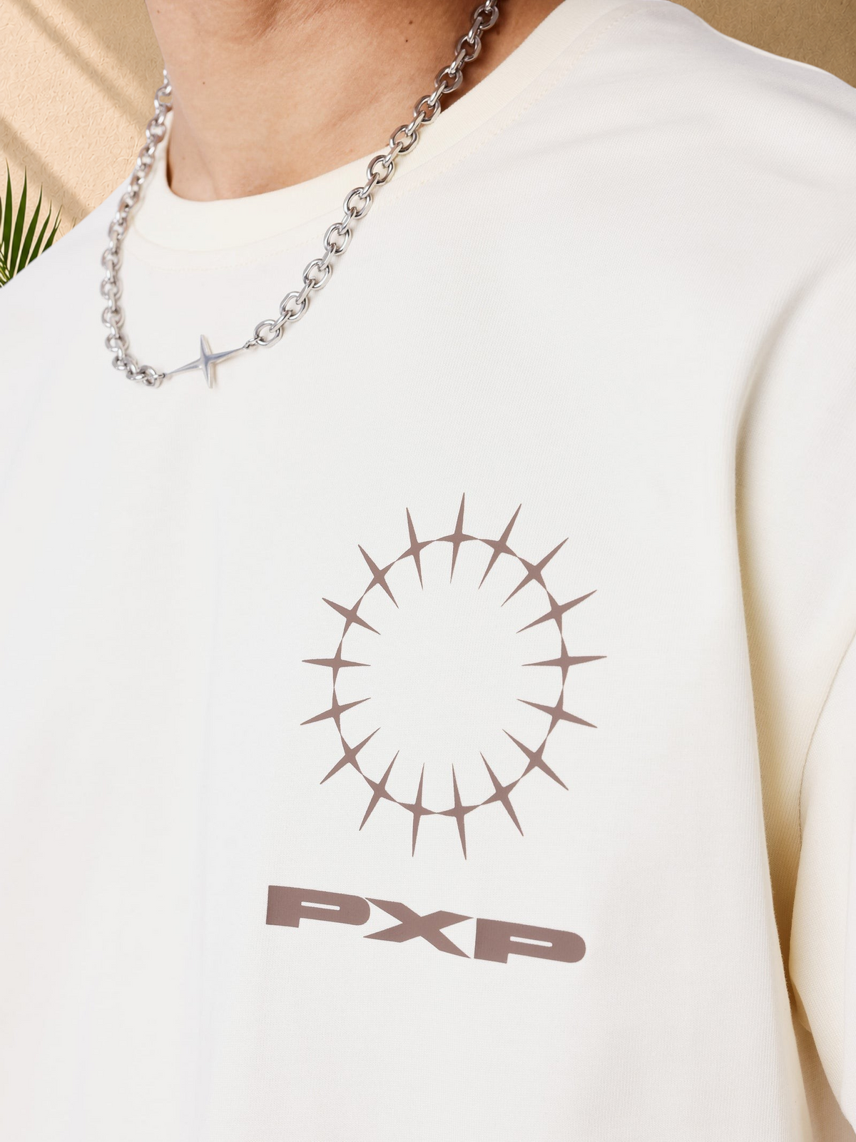 Stayin beige oversized cotton t-shirt with a brown circular graphic and PXP logo on the chest