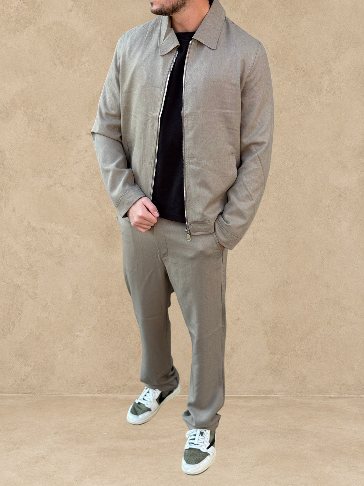 Homme portant un ensemble Stayin beige foncé avec veste zippée décontractée et pantalon coupe droite
