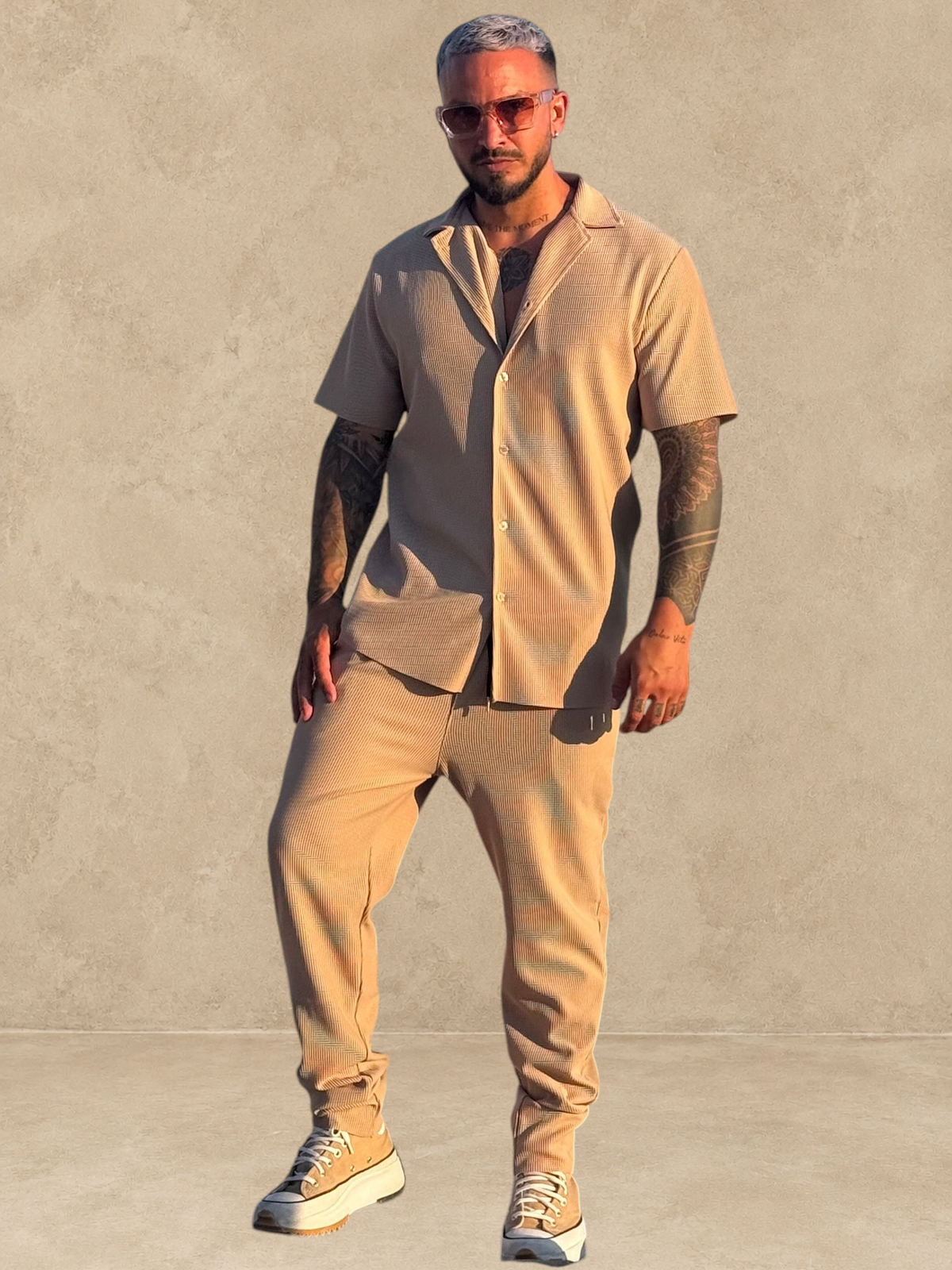Ensemble Stayin beige composé d'une chemise à manches courtes et d'un pantalon droit porté par un homme au bord de mer