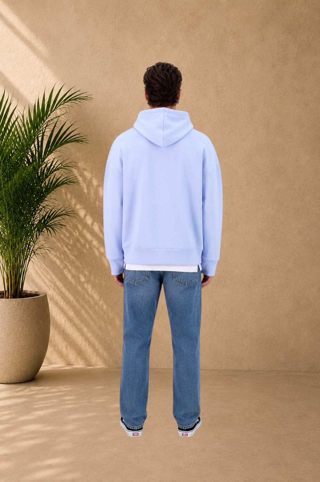 Back view of a man wearing a Stayin light blue quilted hoodie with a hood, paired with blue jeans.
