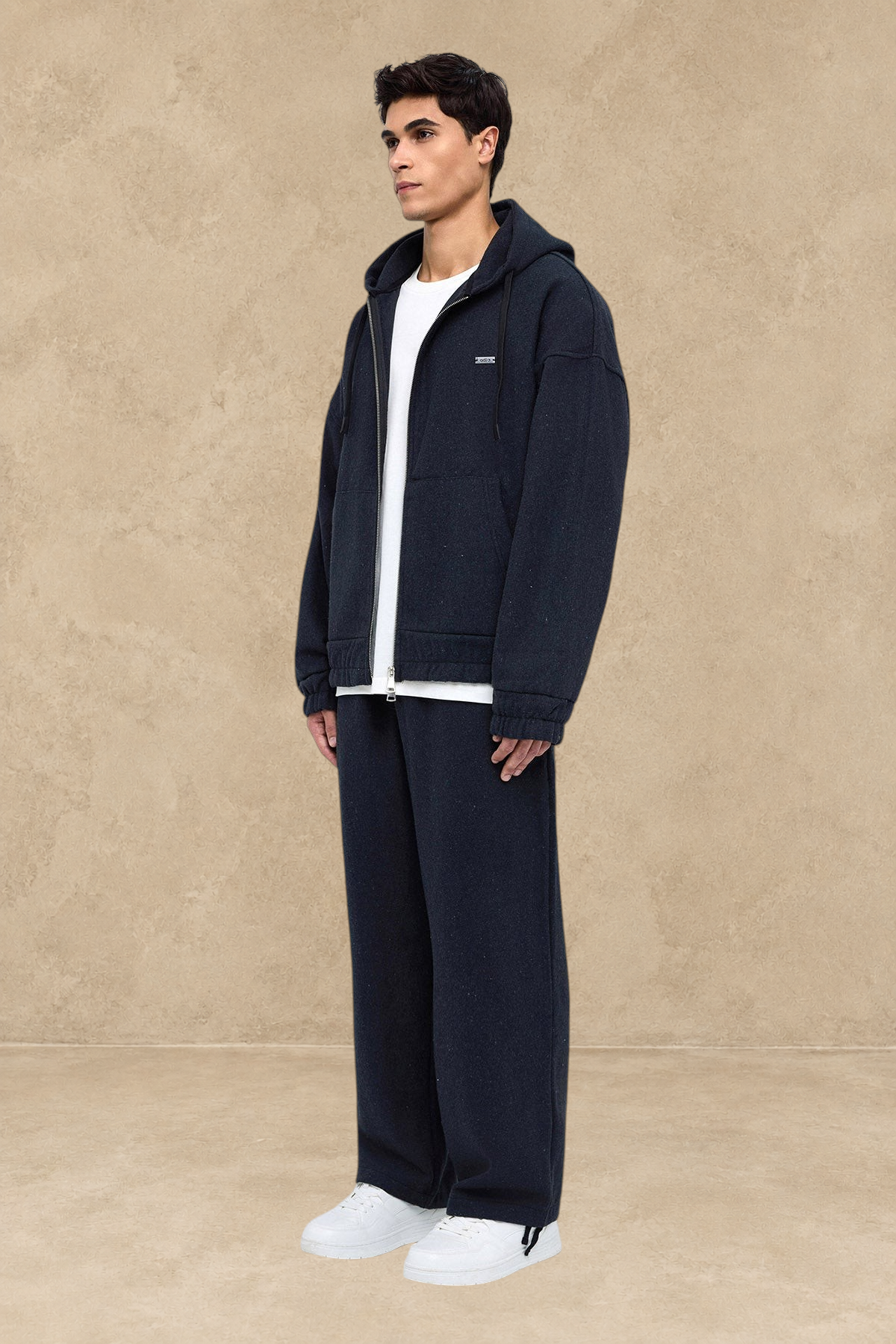 Homme portant un pantalon Oxford noir Stayin à coupe large avec un sweat à capuche assorti et des baskets blanches