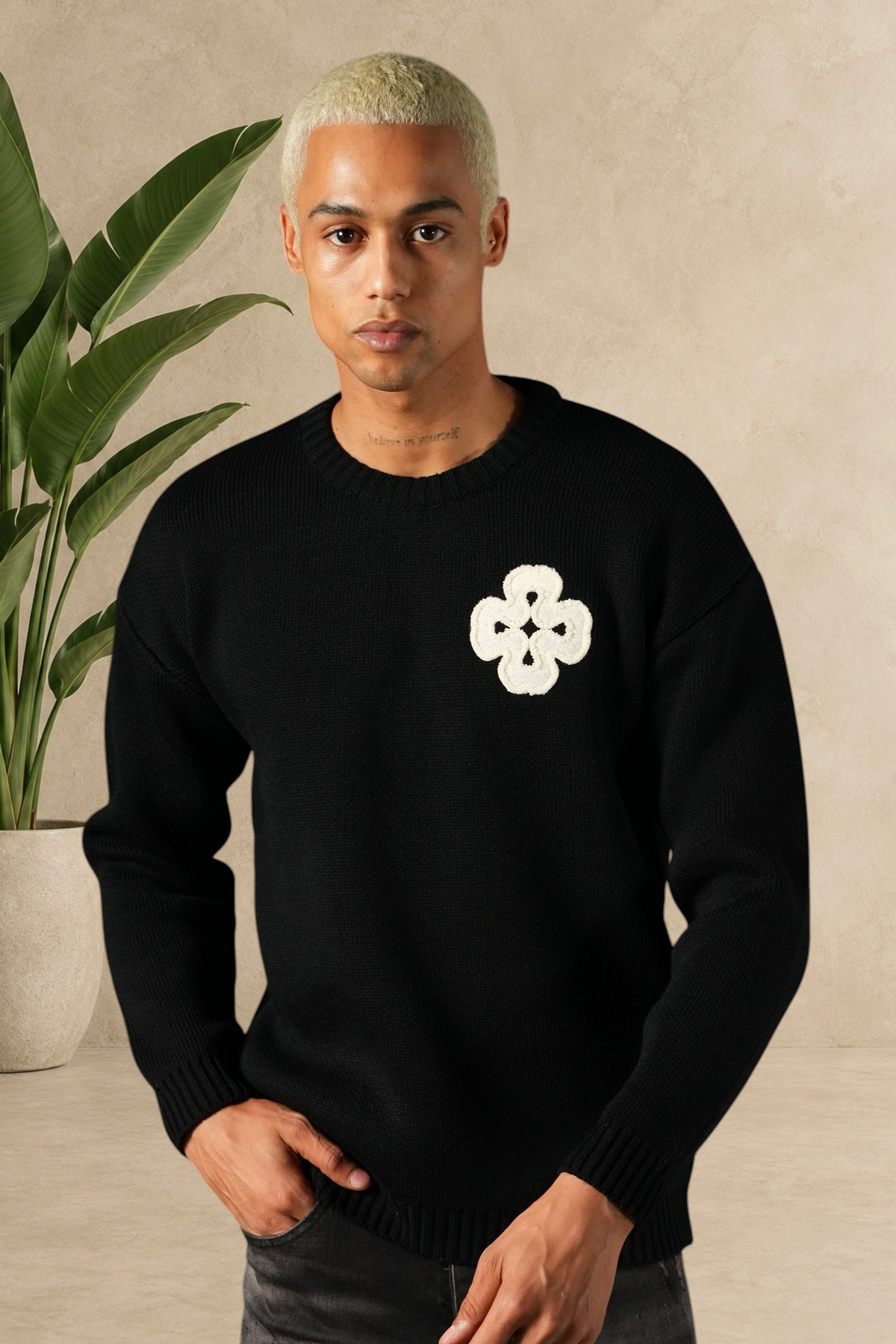 Mannequin portant un pull Stayin noir en maille épaisse avec un motif trèfle blanc brodé sur la poitrine