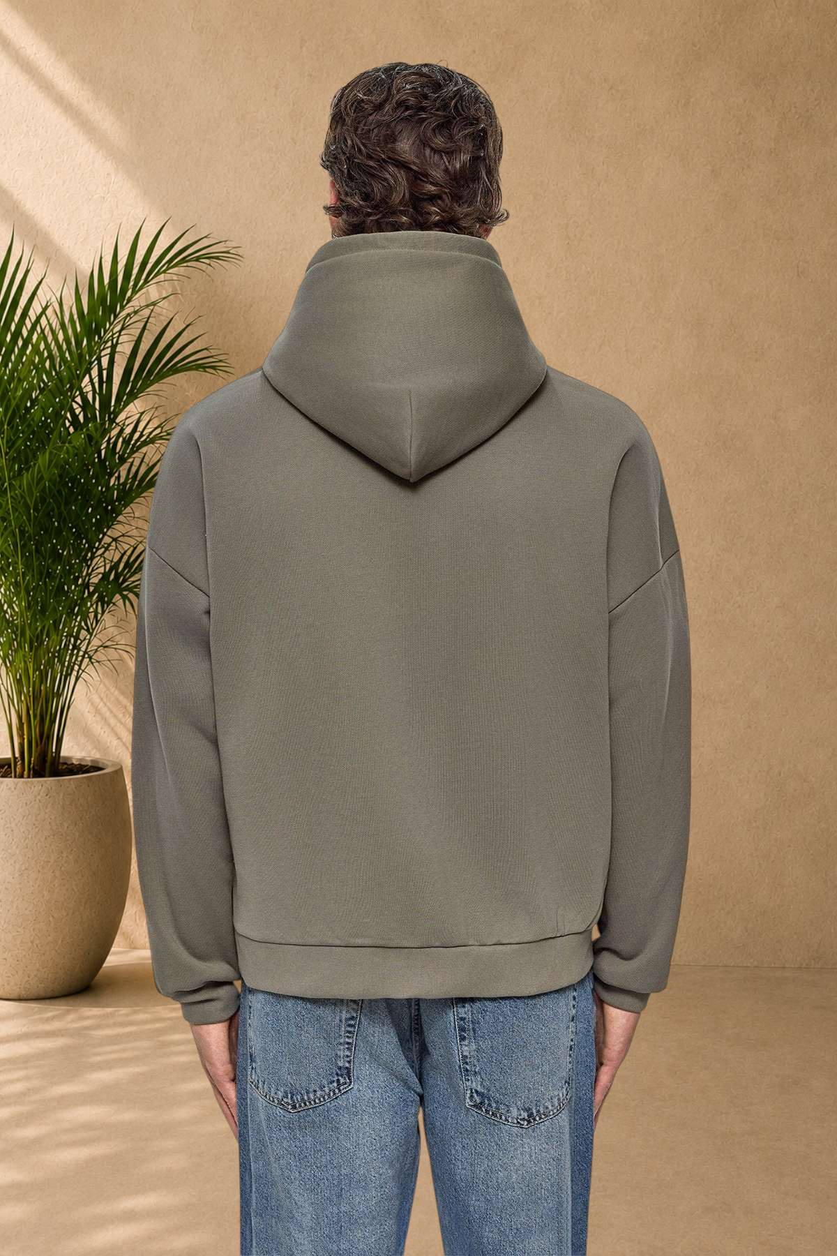Back view of a man wearing a Stayin khaki quilted hooded sweatshirt with a relaxed fit and drop shoulders.