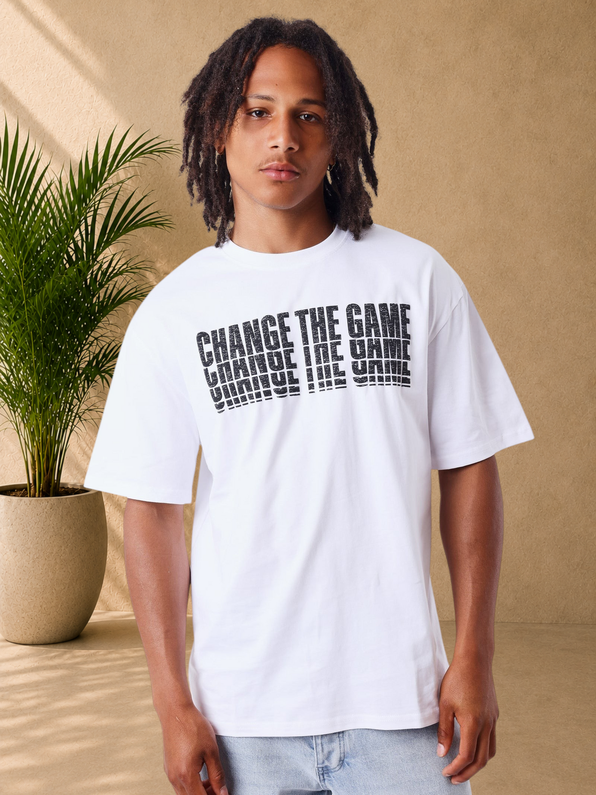 Stayin white cotton t-shirt with black layered typography print on chest, worn by a model in a studio setting.