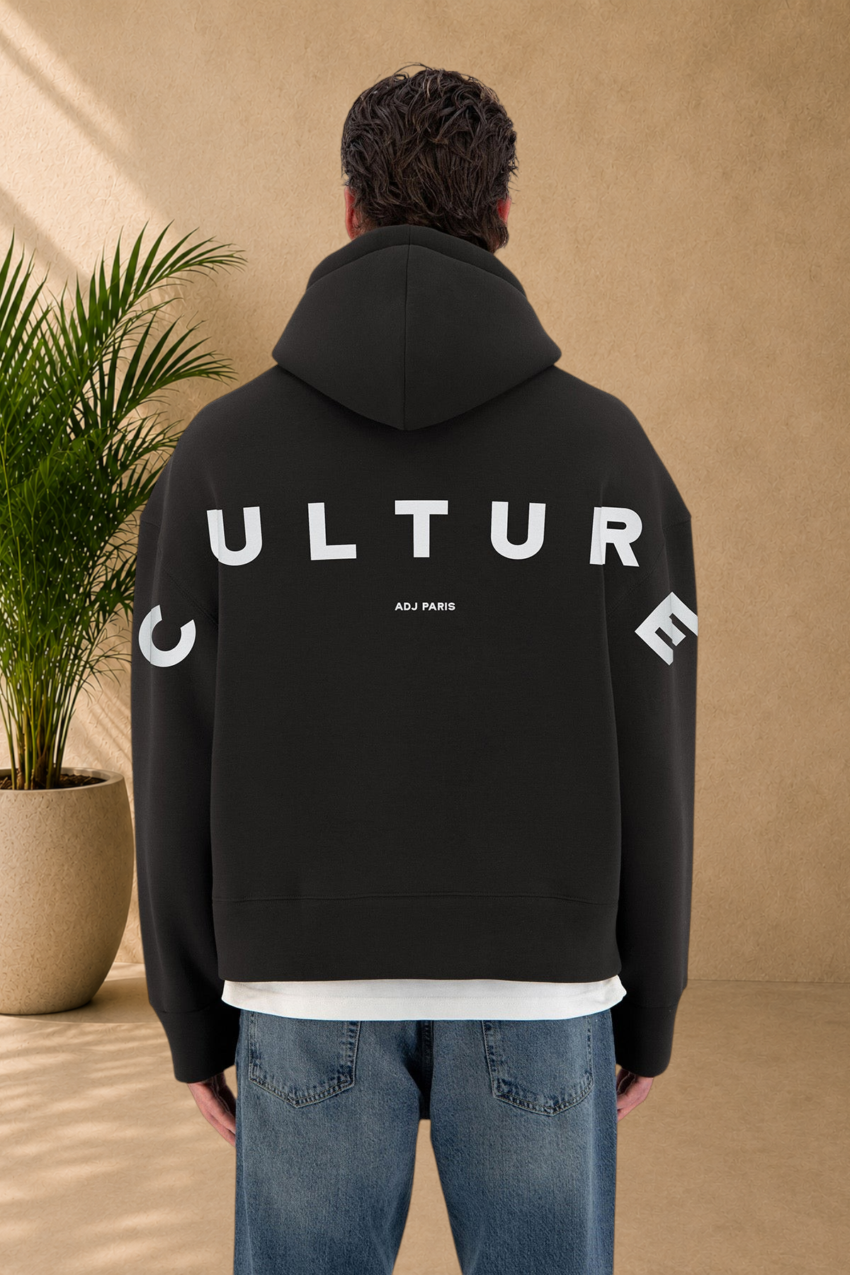 Stayin black quilted hoodie with white Culture text on the back worn by a model in jeans