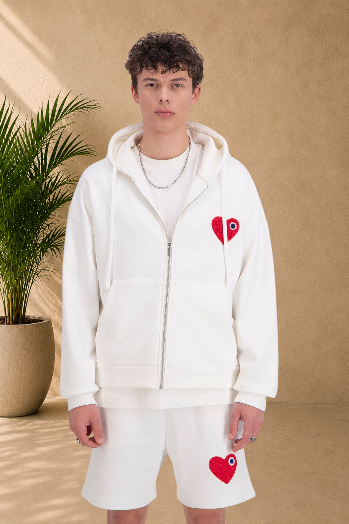 Stayin white zip-up hooded sweatshirt featuring a red heart patch on the chest, worn by a male model.