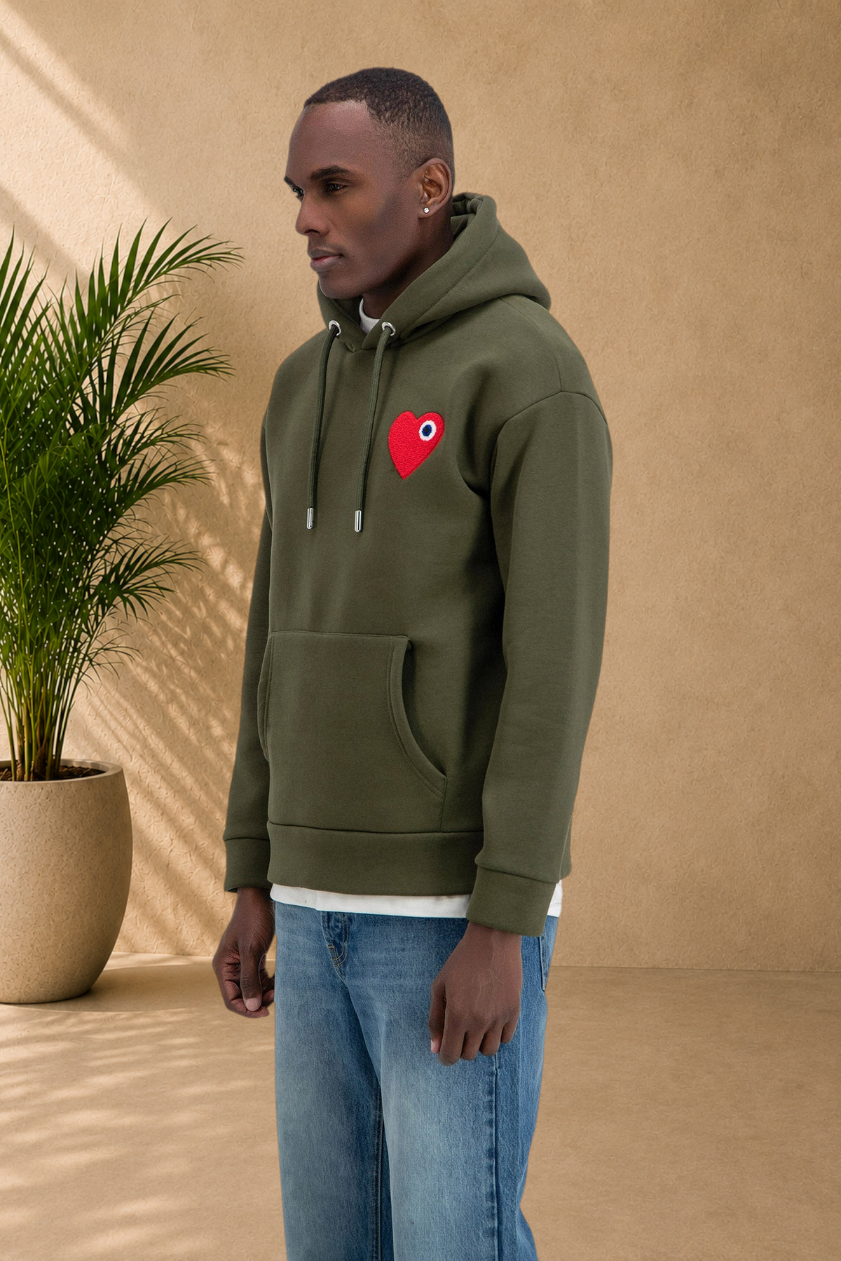 Stayin khaki hooded sweatshirt with a red heart patch worn by a male model in jeans