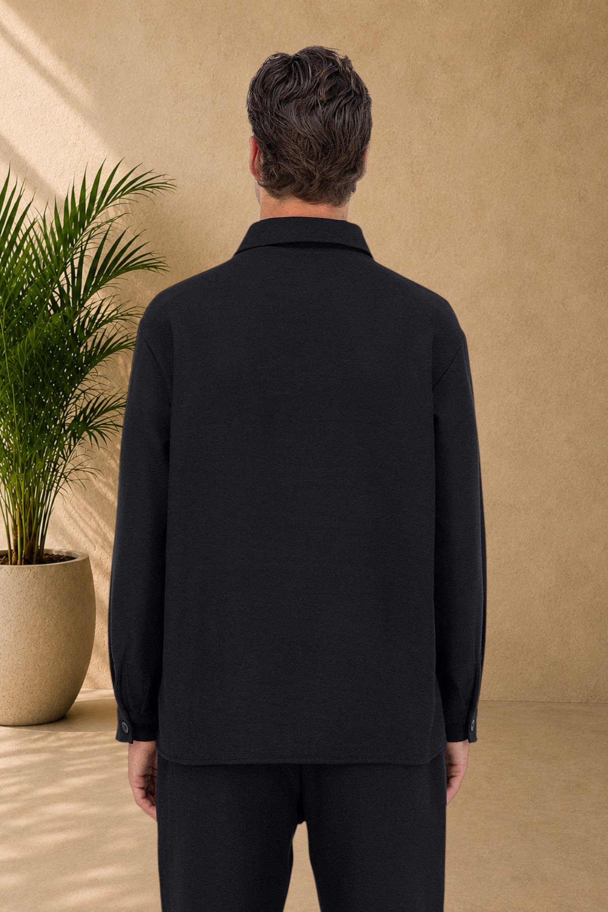 Back view of a man wearing a Stayin black quilted overshirt with a classic collar and long sleeves.