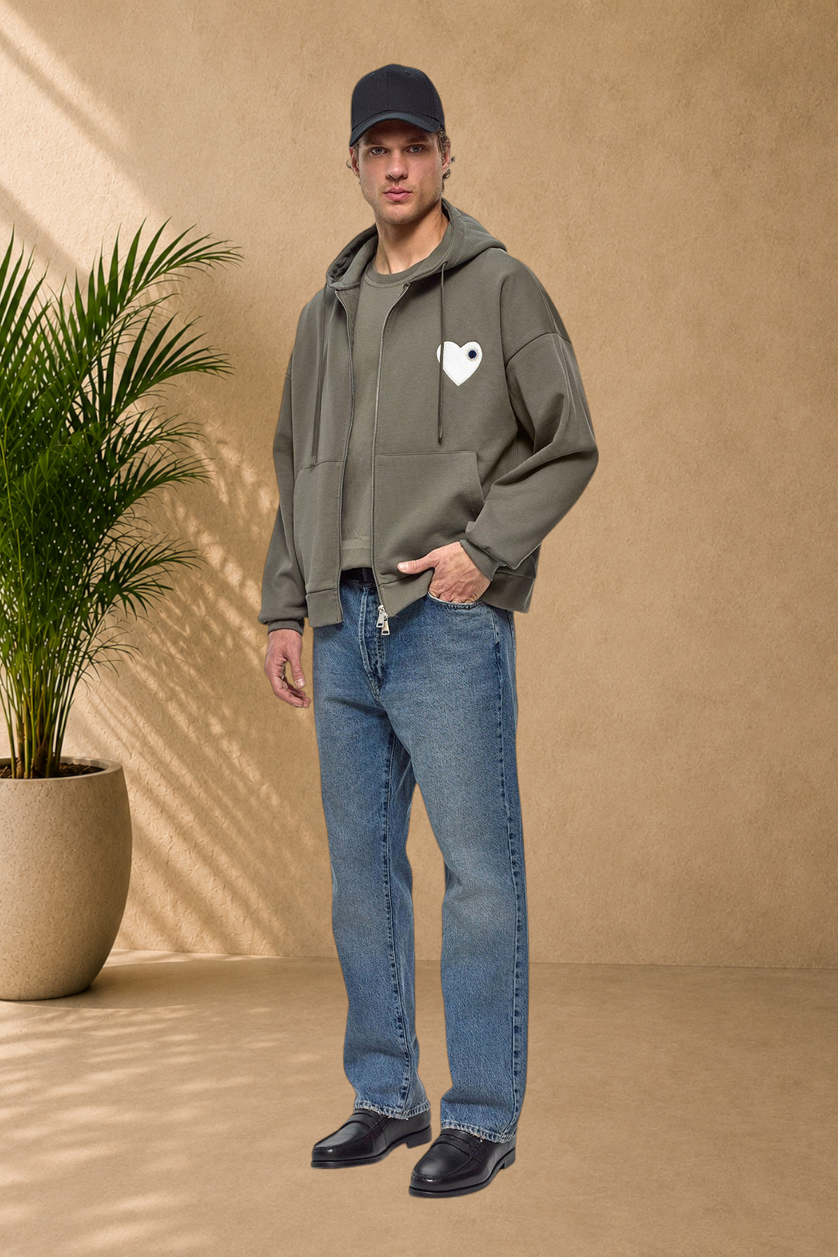 Stayin khaki quilted zip-up hoodie with a white heart patch worn by a male model with blue jeans and a black cap