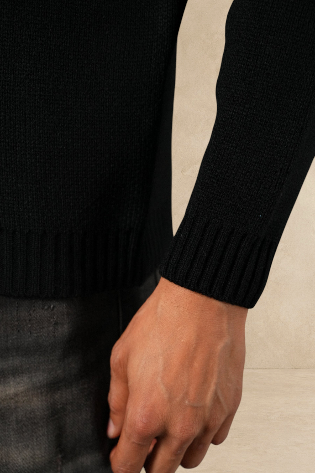 Gros plan sur la manche en maille épaisse noire du pull Stayin porté par un mannequin