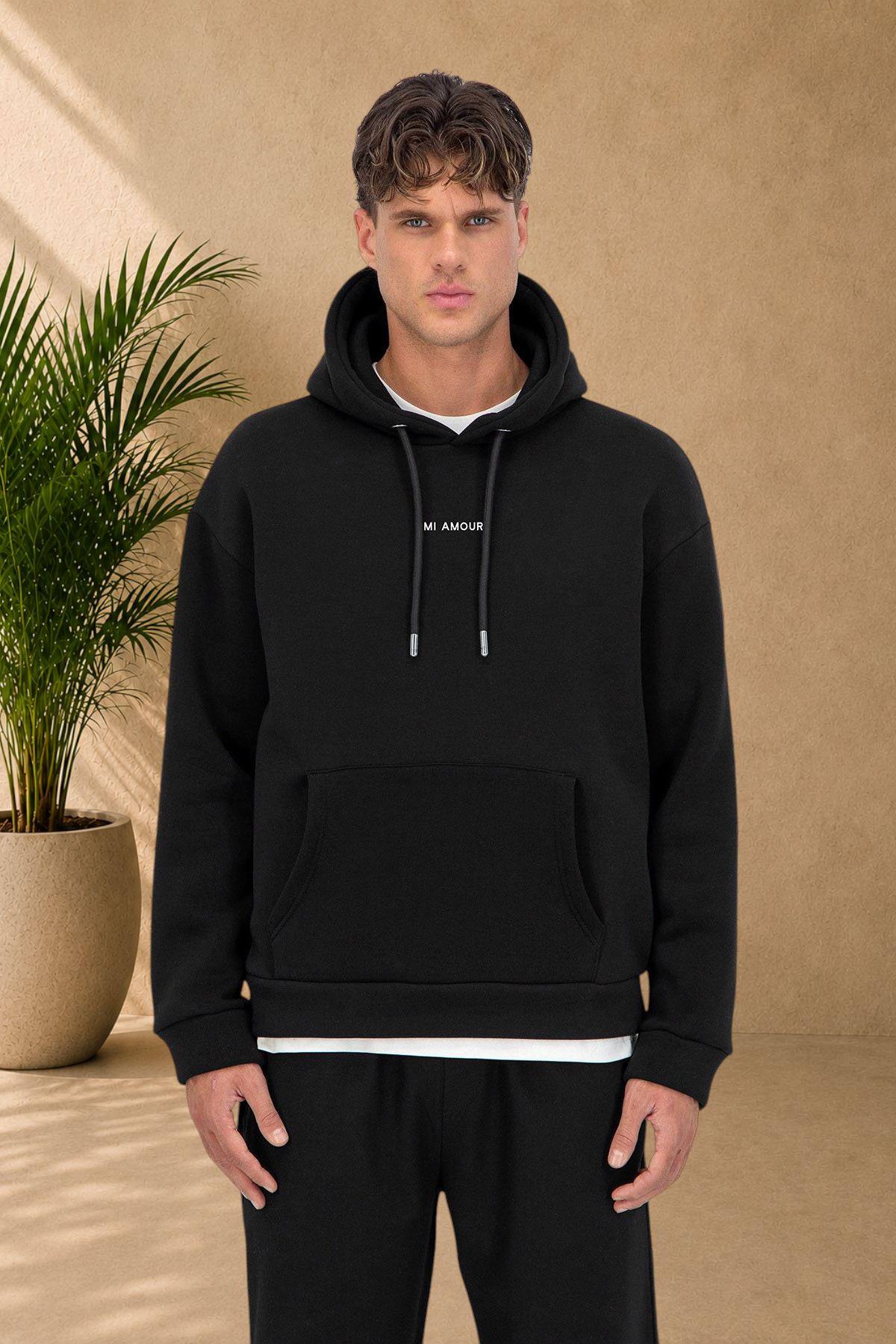 Stayin black quilted hoodie with Amore text, worn by a male model, featuring a thick fabric and front pocket.