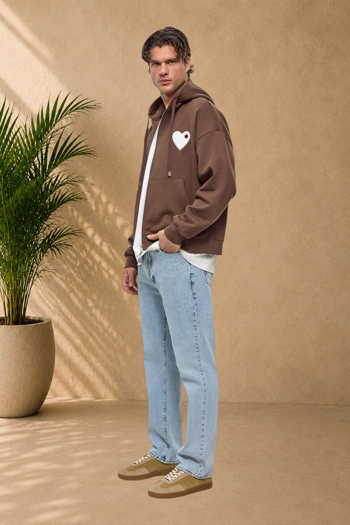 Stayin brown quilted zip-up hoodie with a white heart patch worn by a male model with light blue jeans