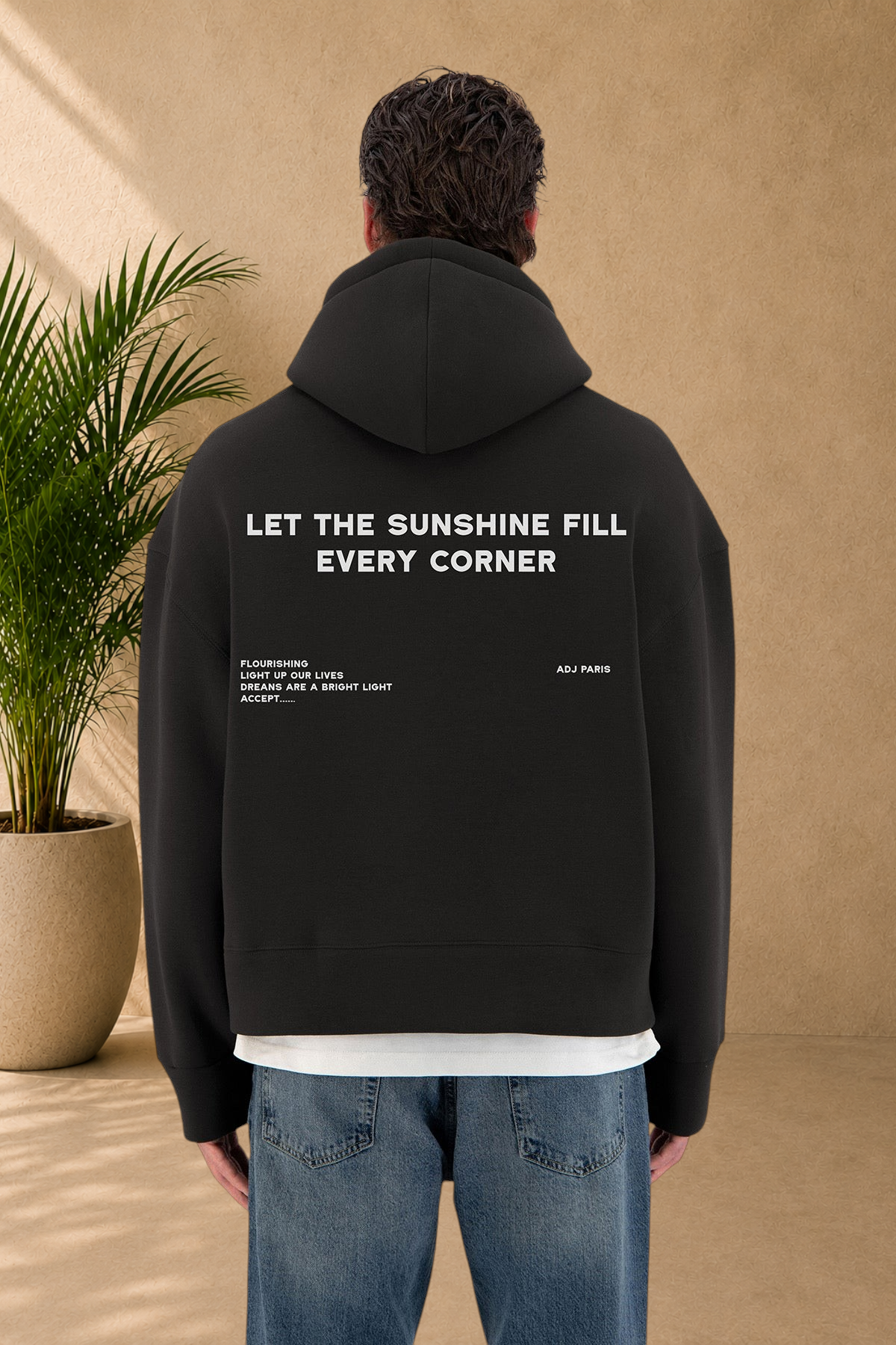 Stayin black quilted hoodie with white text print on back worn by a model in blue jeans