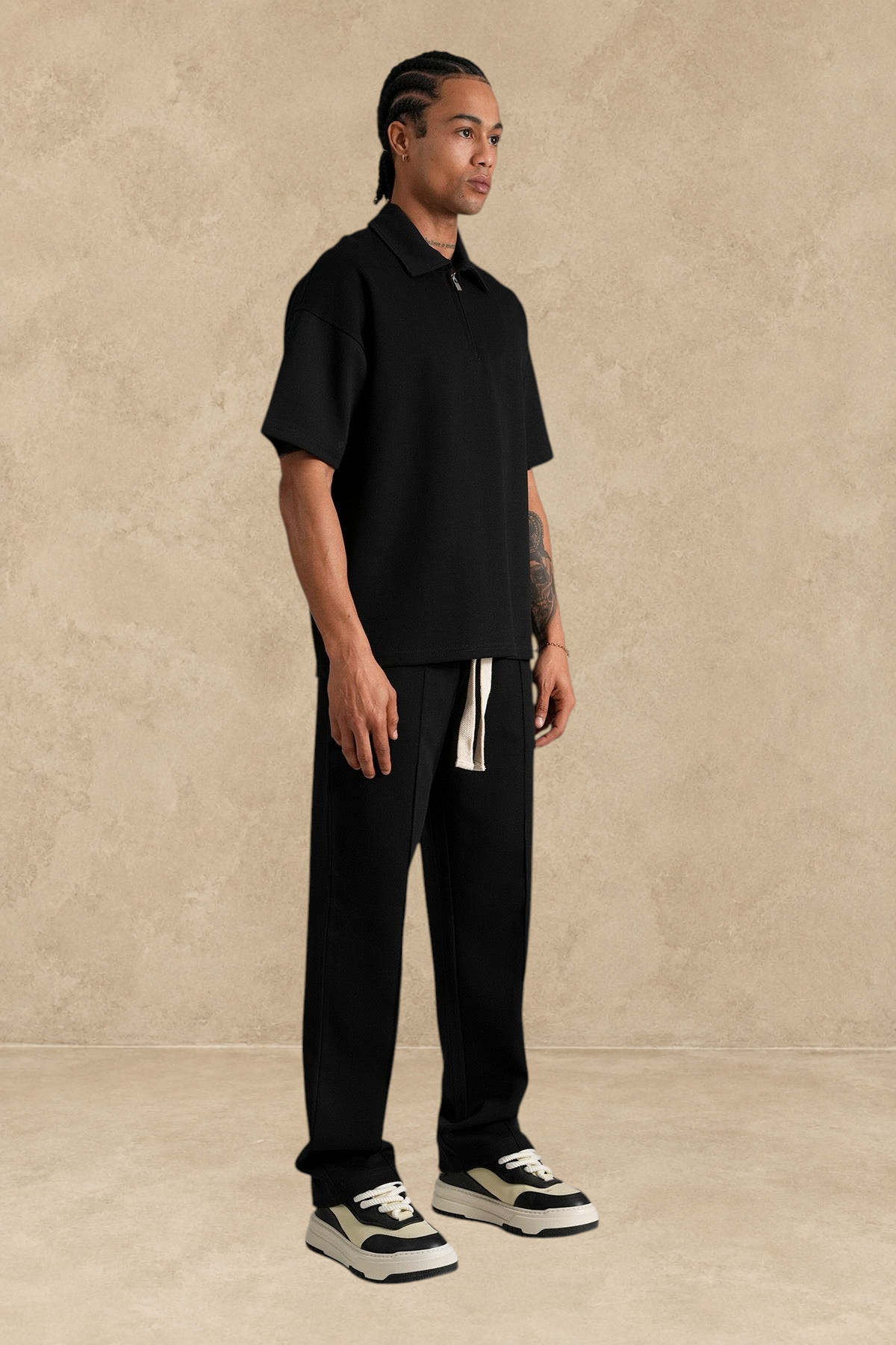 Ensemble Stayin noir coupe large avec polo zippé et pantalon en polyester porté par un mannequin