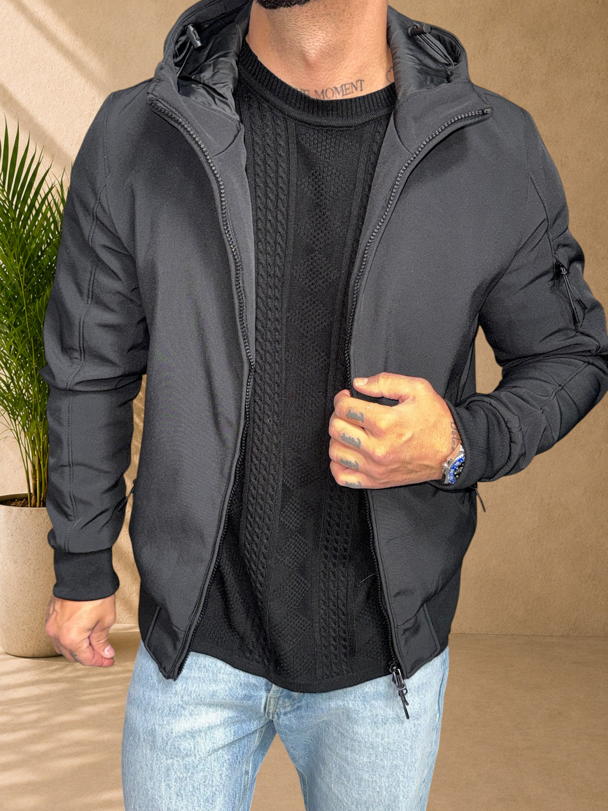 Stayin black hooded windbreaker jacket with zip closure worn by a model over a black cable knit sweater