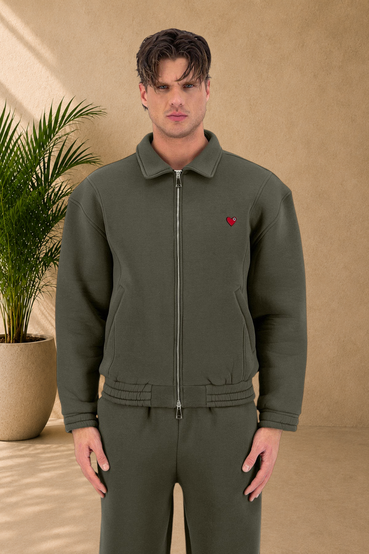 Stayin khaki padded zip-up jacket with a small red heart detail worn by a male model in a studio setting