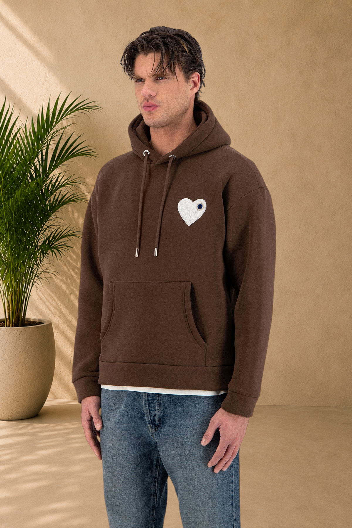 Stayin brown quilted hoodie with a white heart patch on the chest worn by a male model