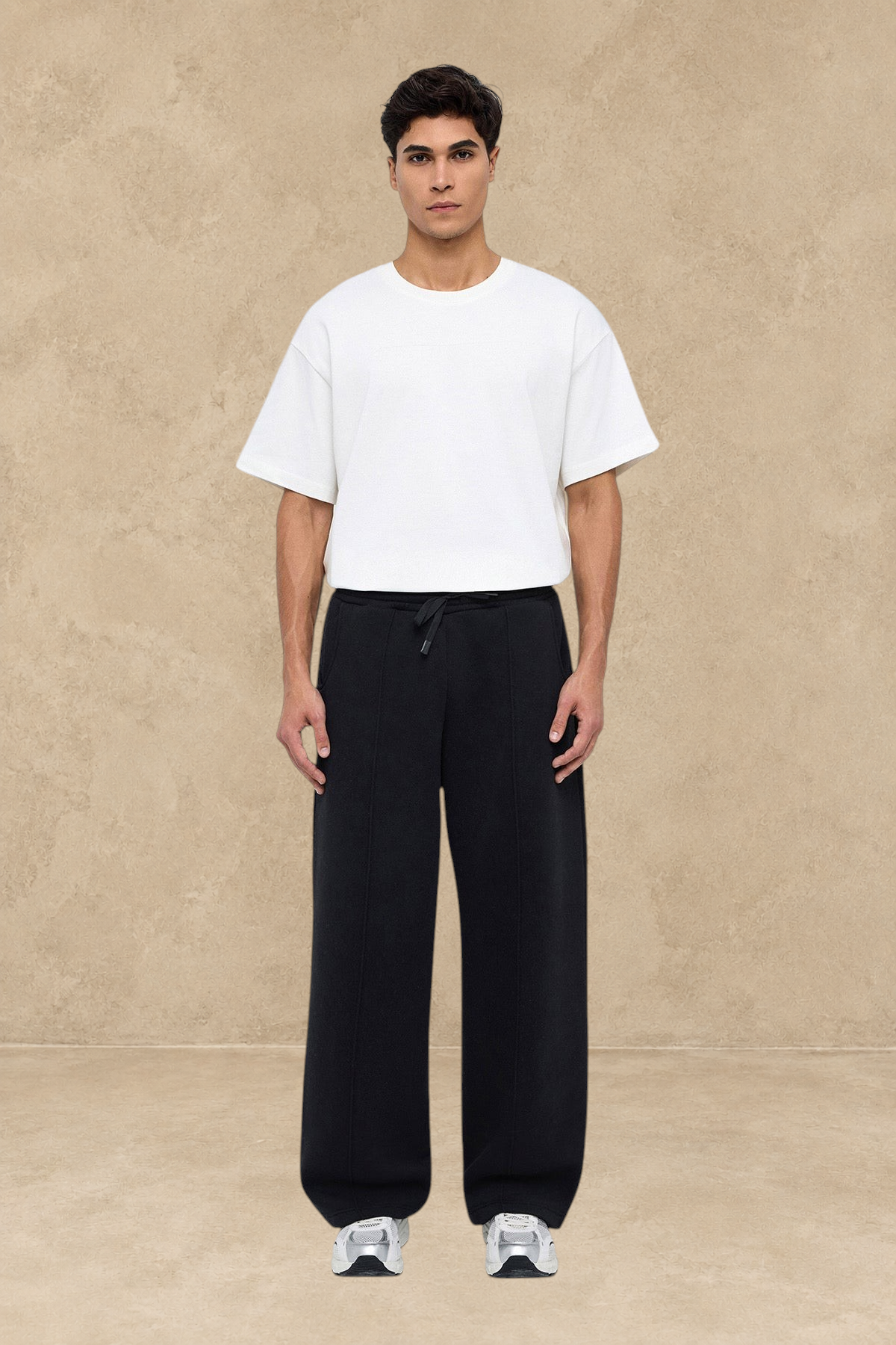 Homme portant un pantalon jogging large noir Stayin avec un t-shirt blanc et des baskets sur fond blanc
