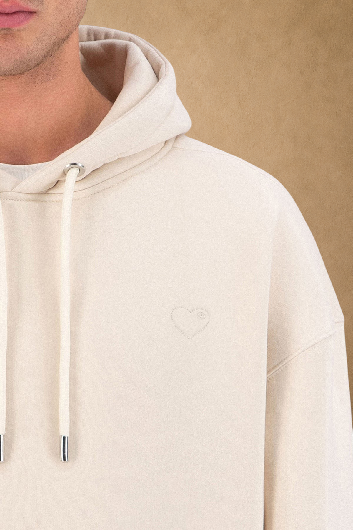 Stayin beige quilted hoodie featuring a small embroidered heart detail on the chest worn by a model