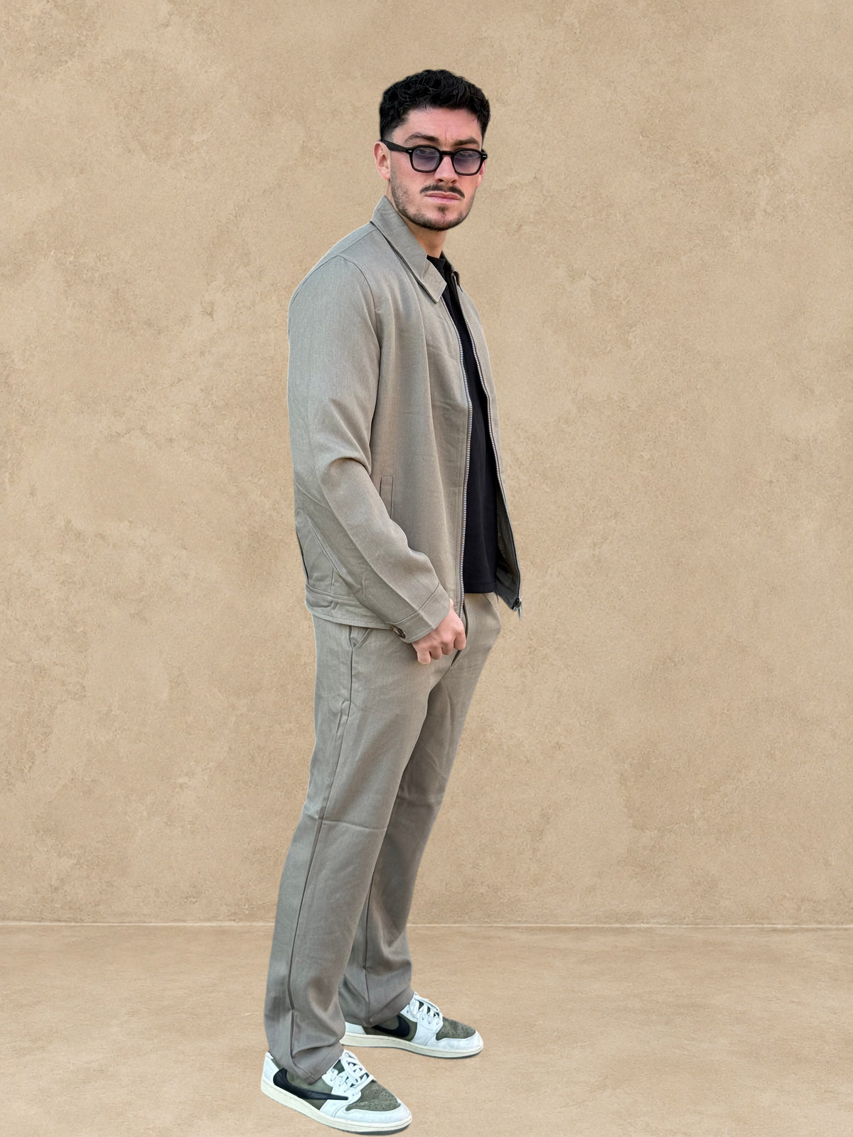 Homme portant un ensemble Stayin beige foncé composé d'une veste zippée décontractée et d'un pantalon coupe droite