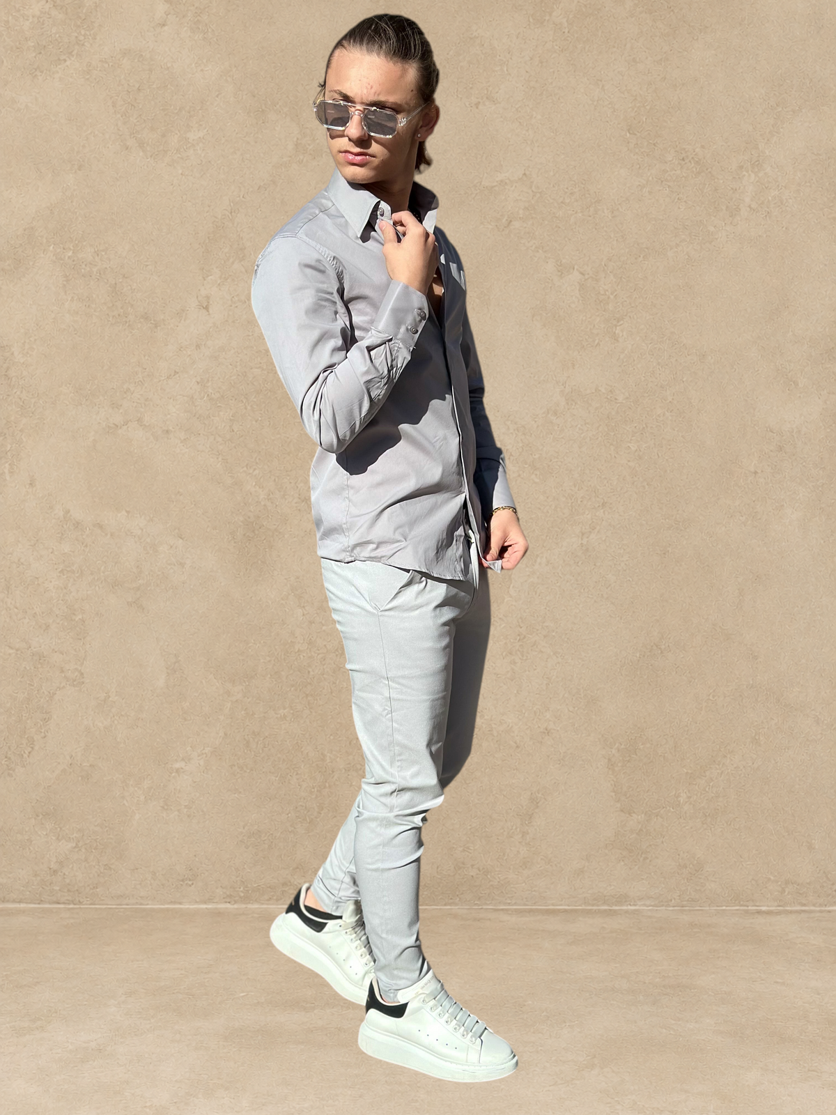 Homme portant un pantalon cosy gris Stayin avec une chemise assortie et des baskets blanches dans une rue ensoleillée