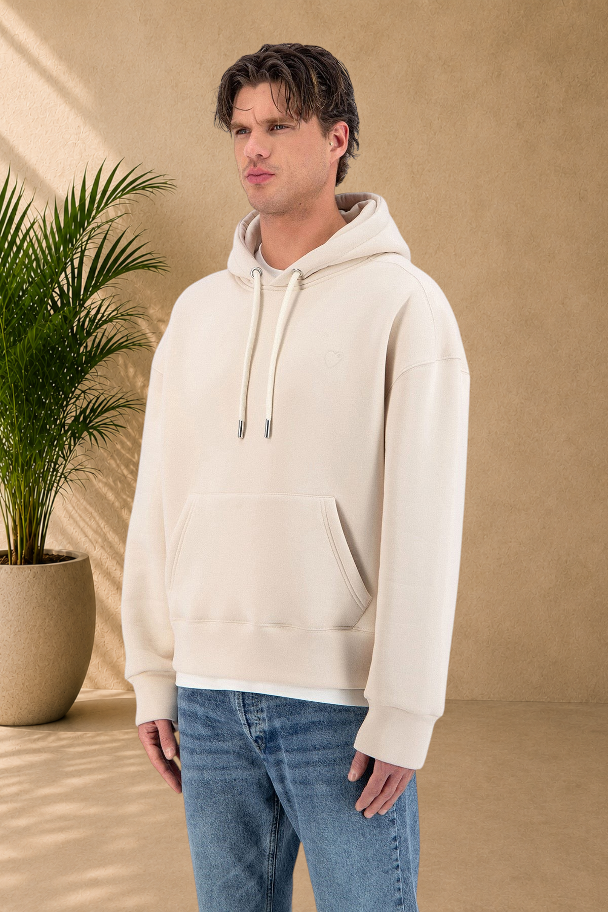Stayin beige quilted hoodie with a small heart detail worn by a male model in jeans