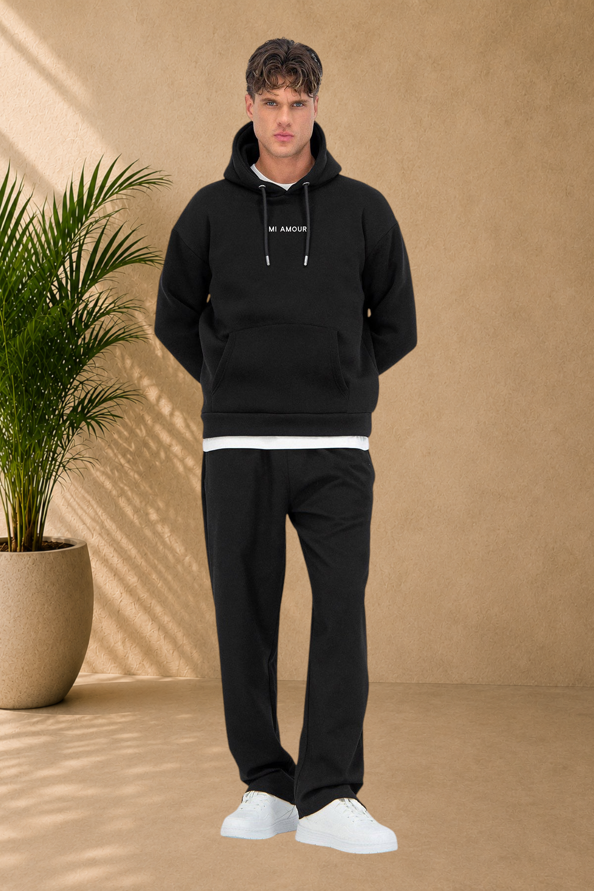 Stayin black quilted hoodie with Mi Amour text, worn by a male model with matching black sweatpants and white sneakers