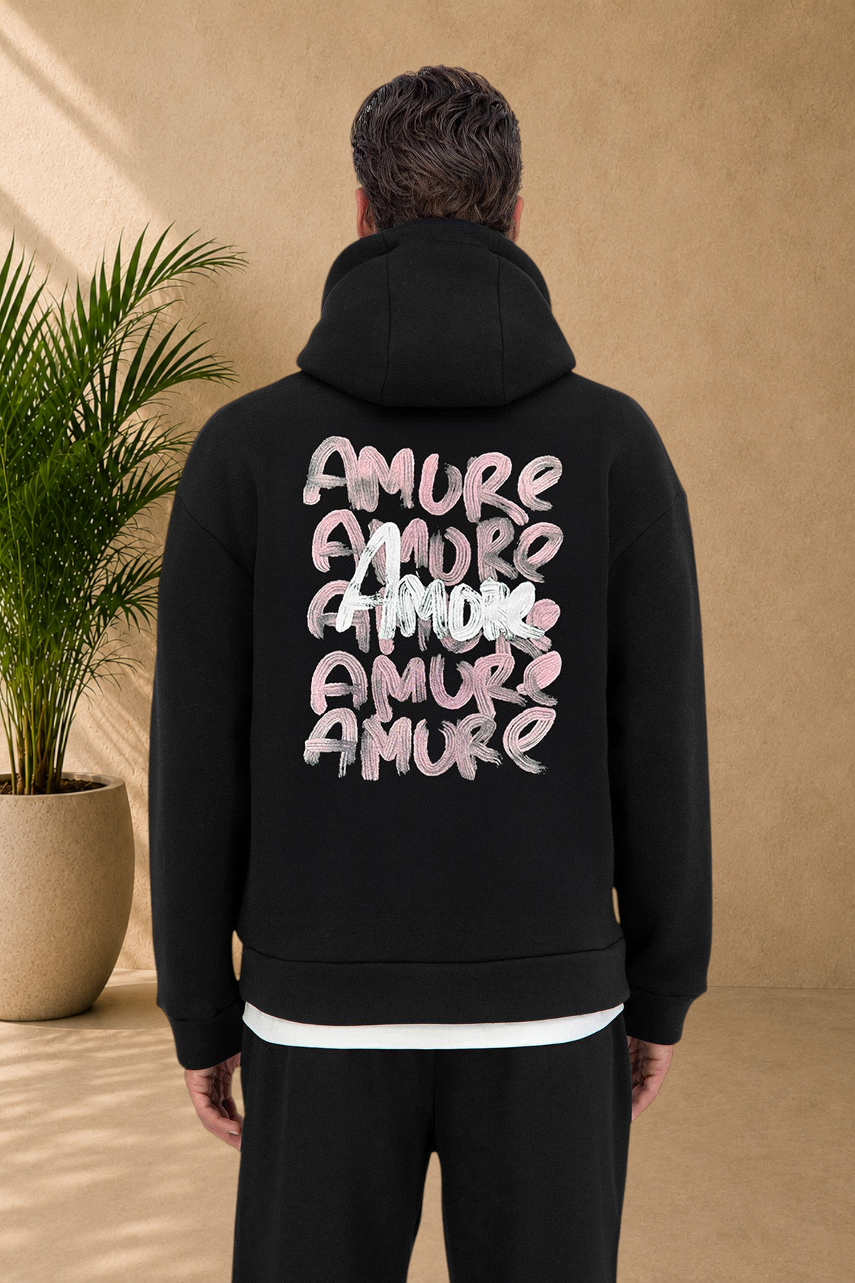 Stayin black hooded sweatshirt with pink and white Amore brushstroke graphic on the back, worn by a model.