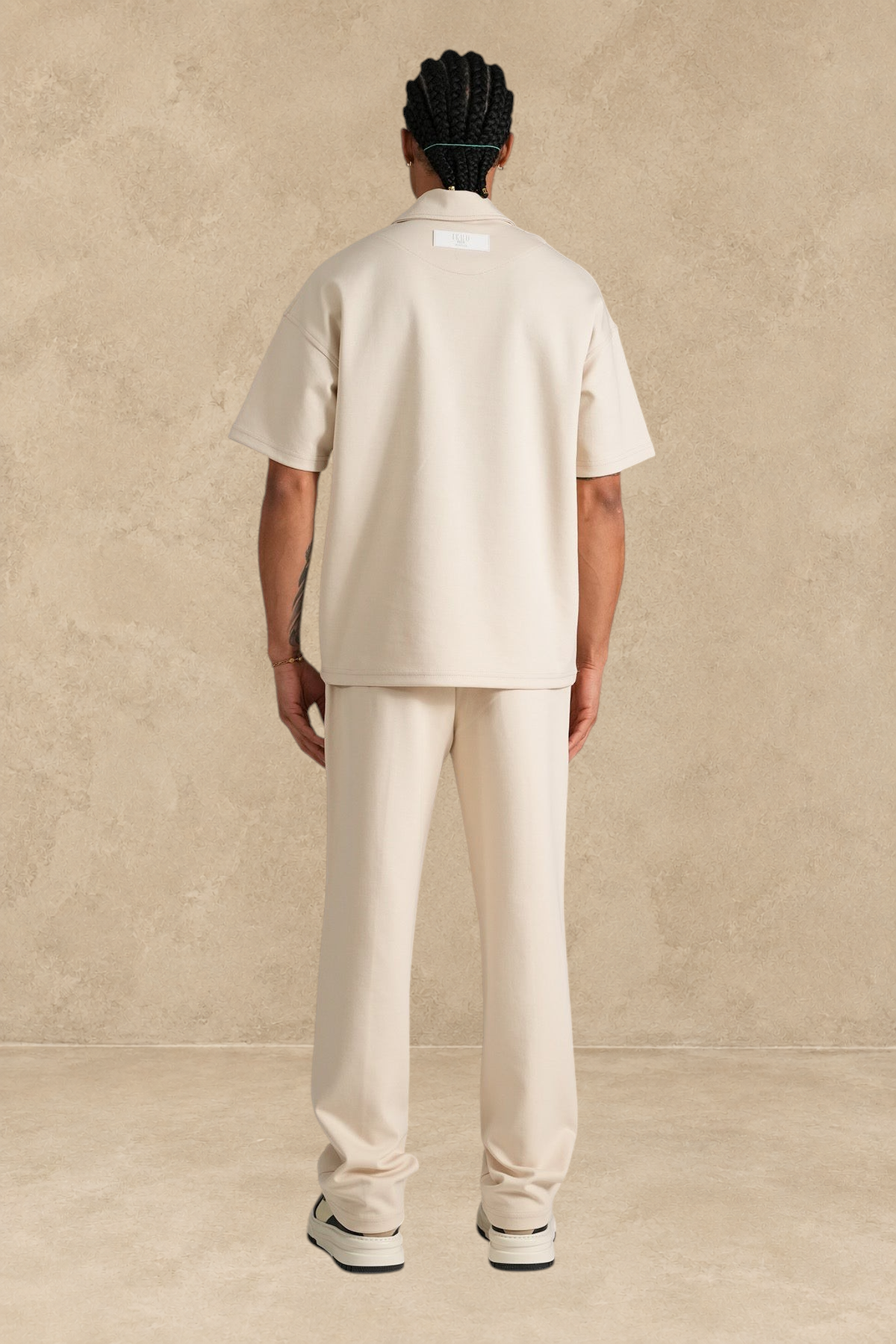 Ensemble Stayin beige coupe large en polyester avec polo zippé et pantalon porté par un mannequin de dos