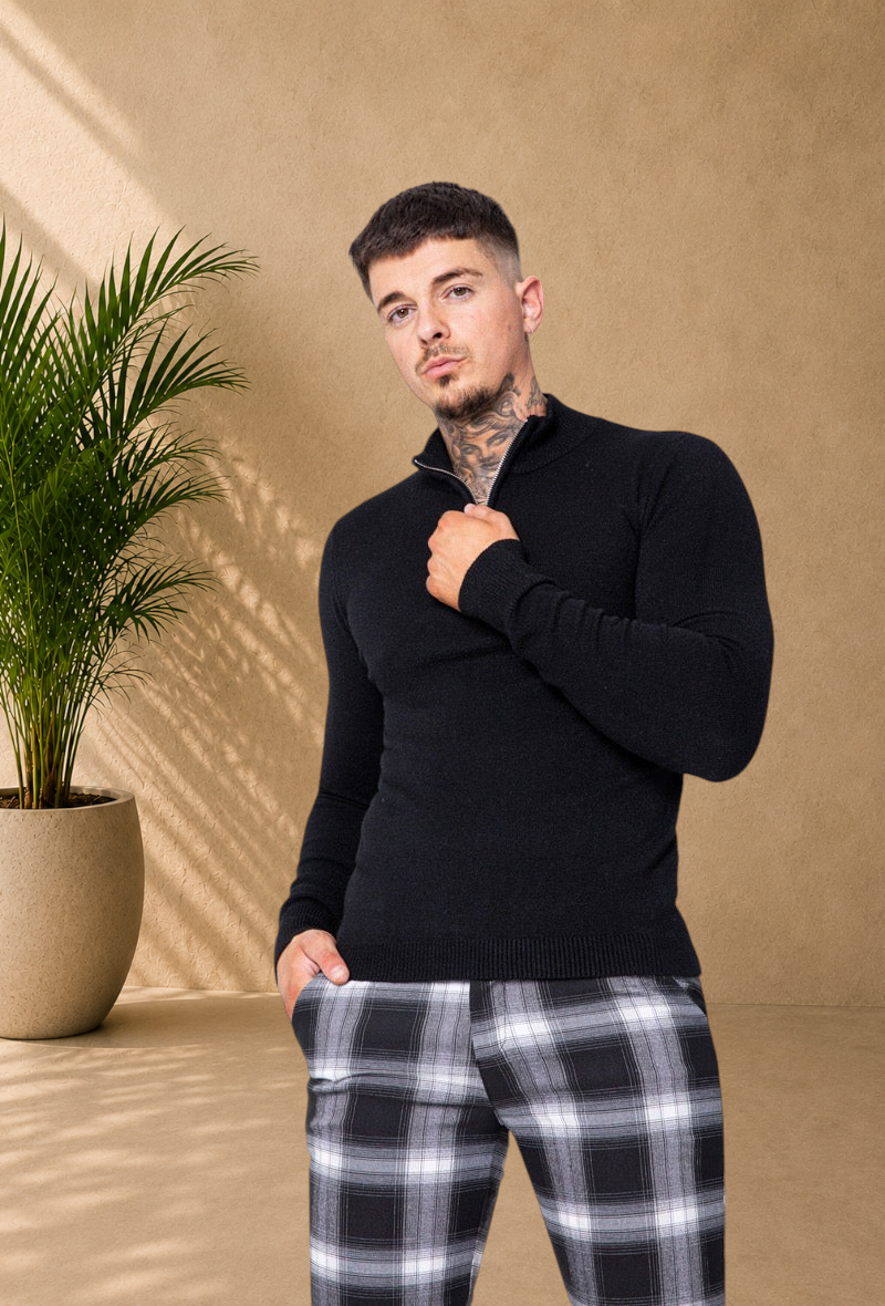 Stayin black knit sweater with a zip-up mock neck worn by a model in a studio setting.