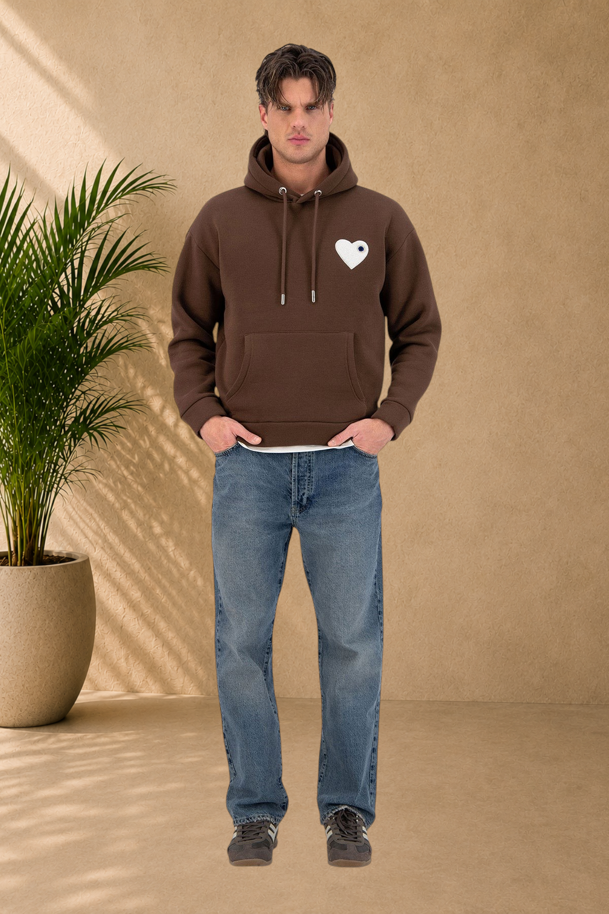 Stayin brown quilted hoodie with a small black heart logo on the chest worn by a male model with blue jeans