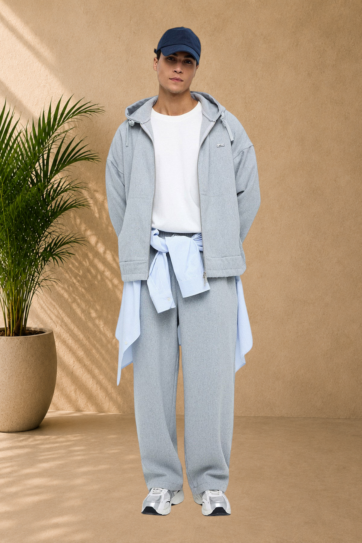 Stayin grey Oxford zip-up jacket worn by a model with a white t-shirt, blue striped shirt, and matching grey trousers