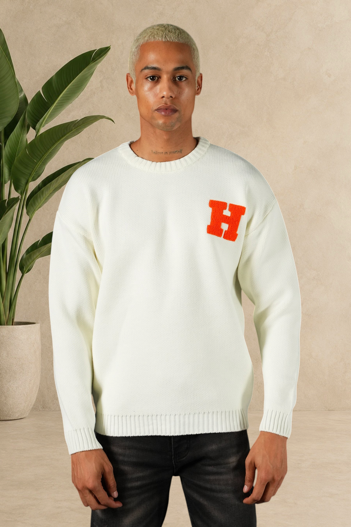 Homme portant un pull Stayin blanc en maille épaisse avec un logo H orange sur la poitrine
