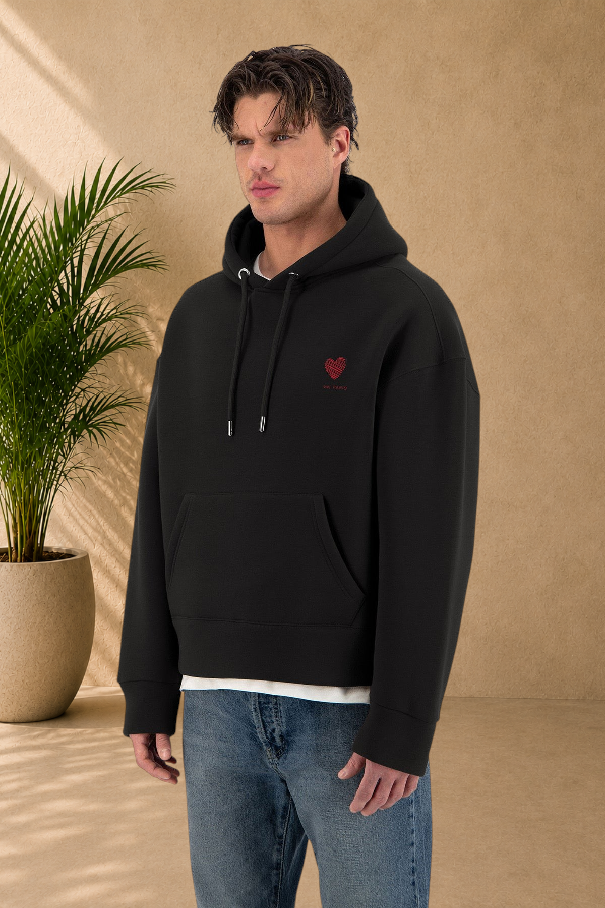 Stayin black hoodie with a red heart embroidery on the chest worn by a male model against a white background