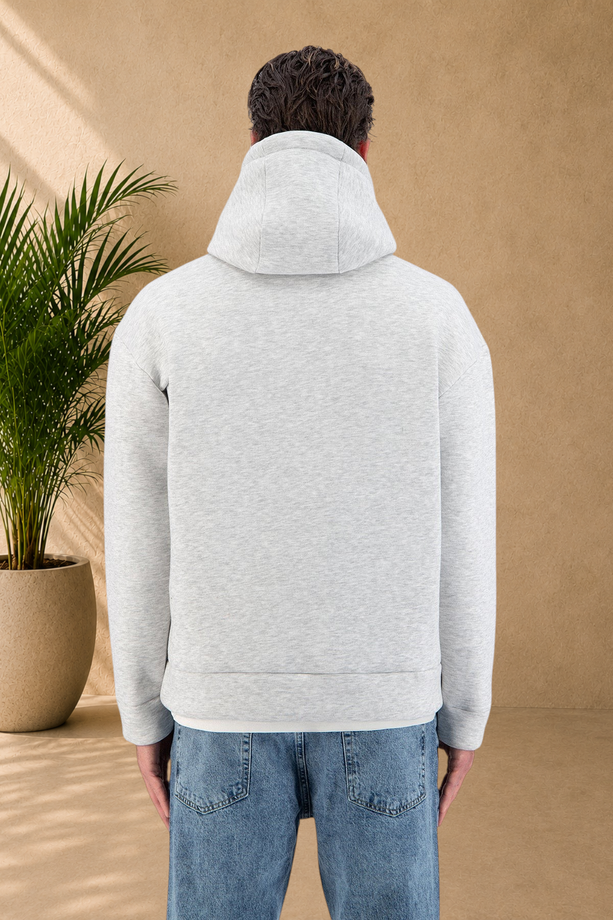 Back view of a model wearing a thick grey Stayin hooded sweatshirt with a quilted texture and blue jeans.