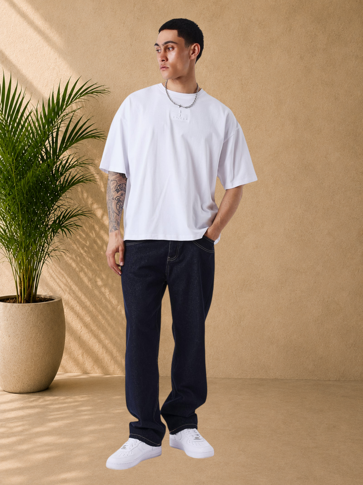 Stayin model wearing a white boxy fit cotton t-shirt with tonal embossed logo detail and short sleeves