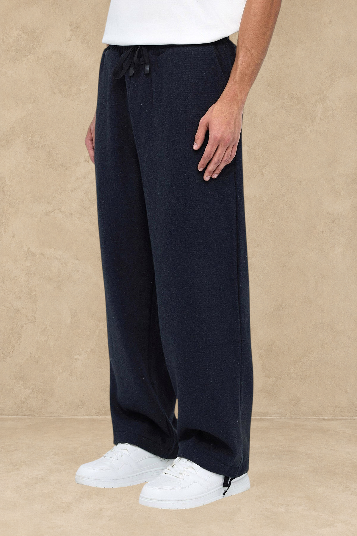 Pantalon Oxford noir Stayin à coupe large avec cordon de serrage, porté par un mannequin avec des baskets blanches